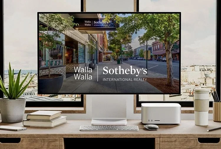Computer monitor on a desk displaying a real estate advertisement for Walla Walla Sotheby's International Realty, with the street scene in Walla Walla, Washington, visible on the screen.