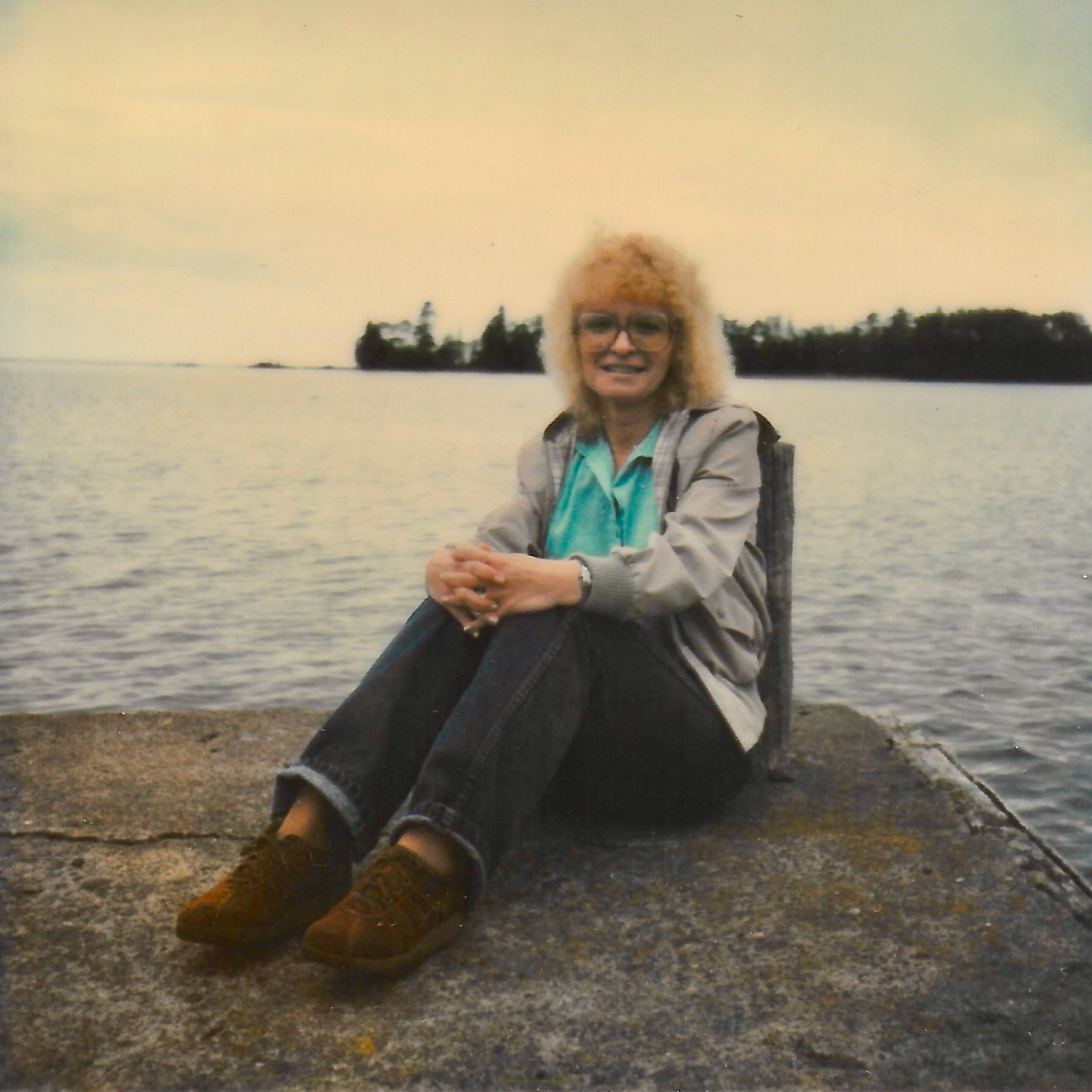 Old photo of woman sitting on rock in front of Lake Superior in the Upper Peninsula of Michigan.