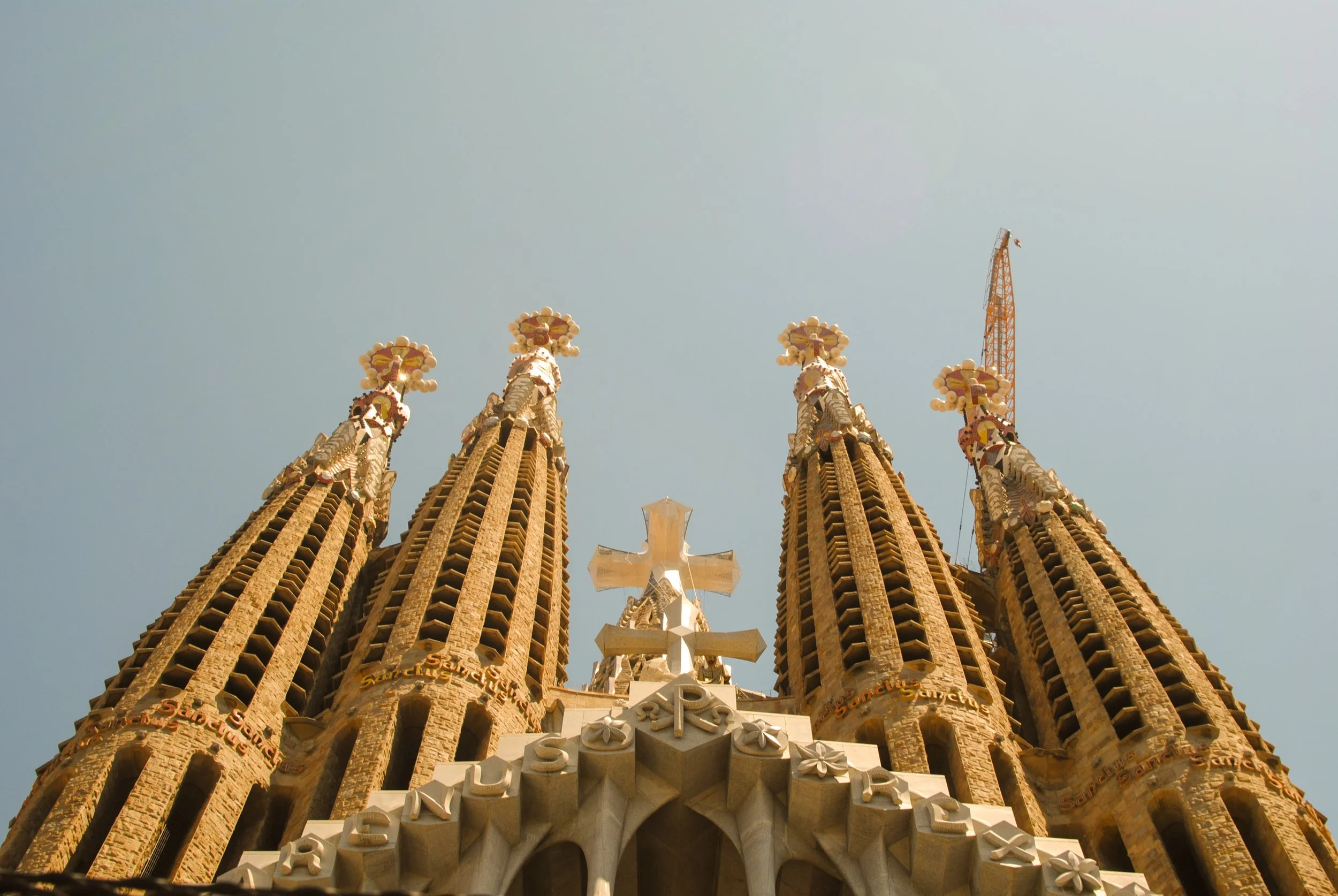 Close-up of the spires and detailed architecture of the Sagrada Família basilica in Barcelona, Spain, with a clear blue sky in the background.
