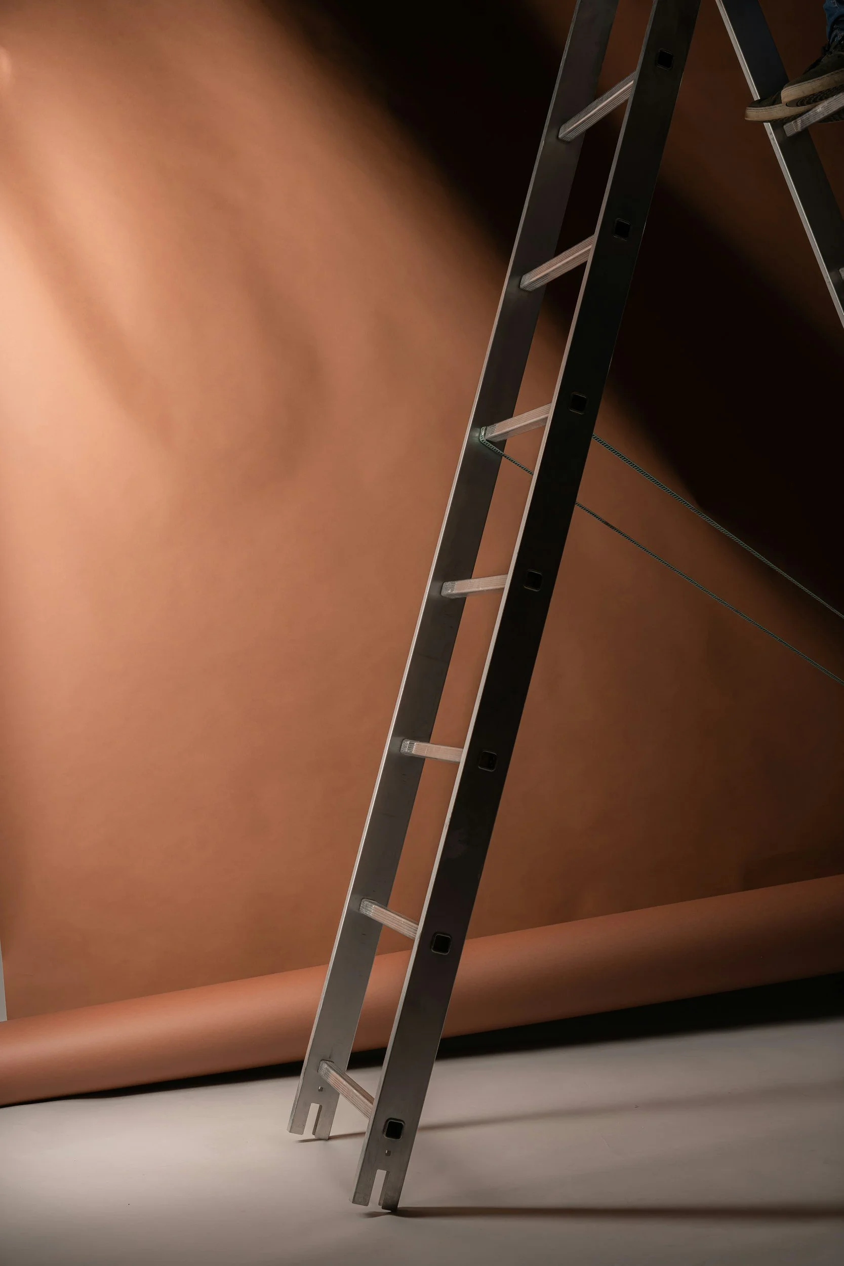 A metal ladder leaning against the ceiling in a room with brown walls.