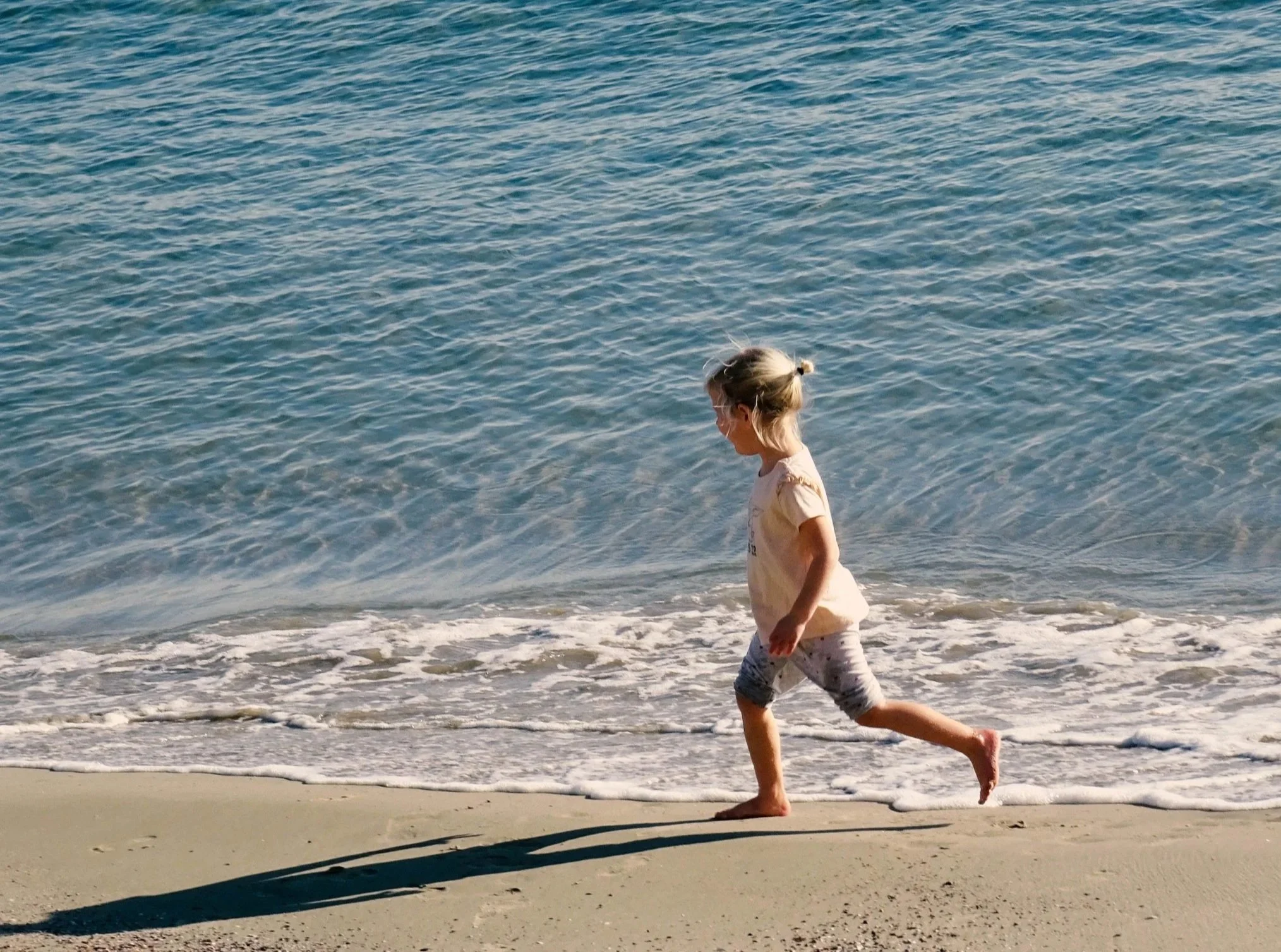 Sensory processing at the beach, young girl running at the shore while regulated