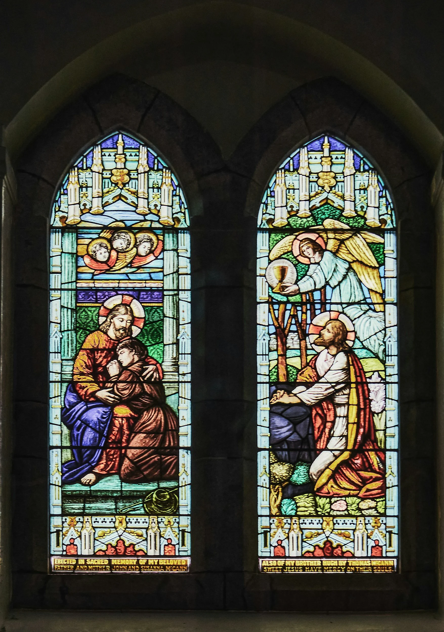 Colorful stained glass church windows depicting religious scenes, including images of Jesus, angels, and biblical figures, with decorative borders and religious inscriptions at the bottom.