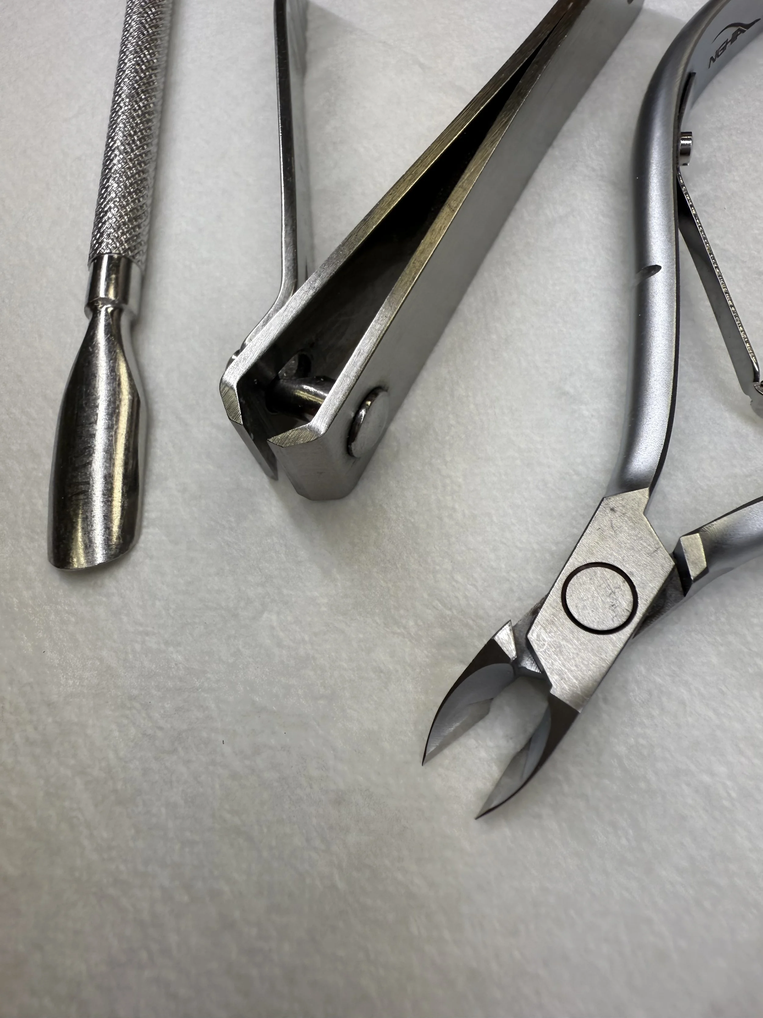 Close-up of dental tools on a light-colored surface, including a dental scaler, a plastic mouth retractor, and a pair of dental pliers.