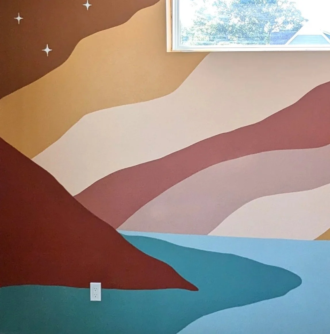 Austin, Texas nursery mural with layered mountain-inspired shapes in earthy tones, pink, blue, and cream.