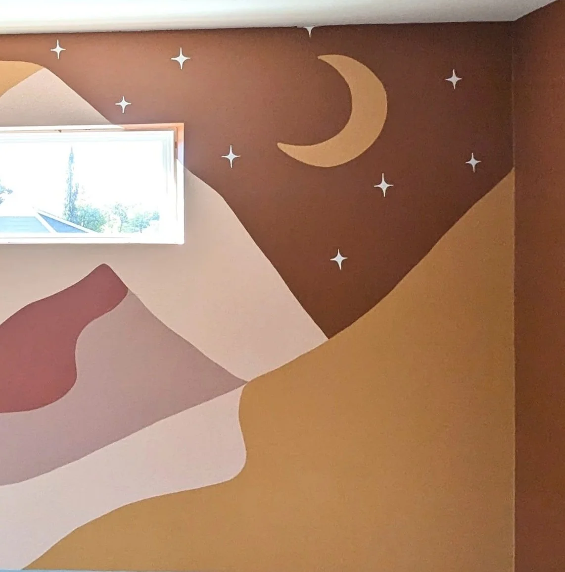 Austin, Texas nursery mural featuring a painted mountain landscape, crescent moon, and stars in earthy boho colors.