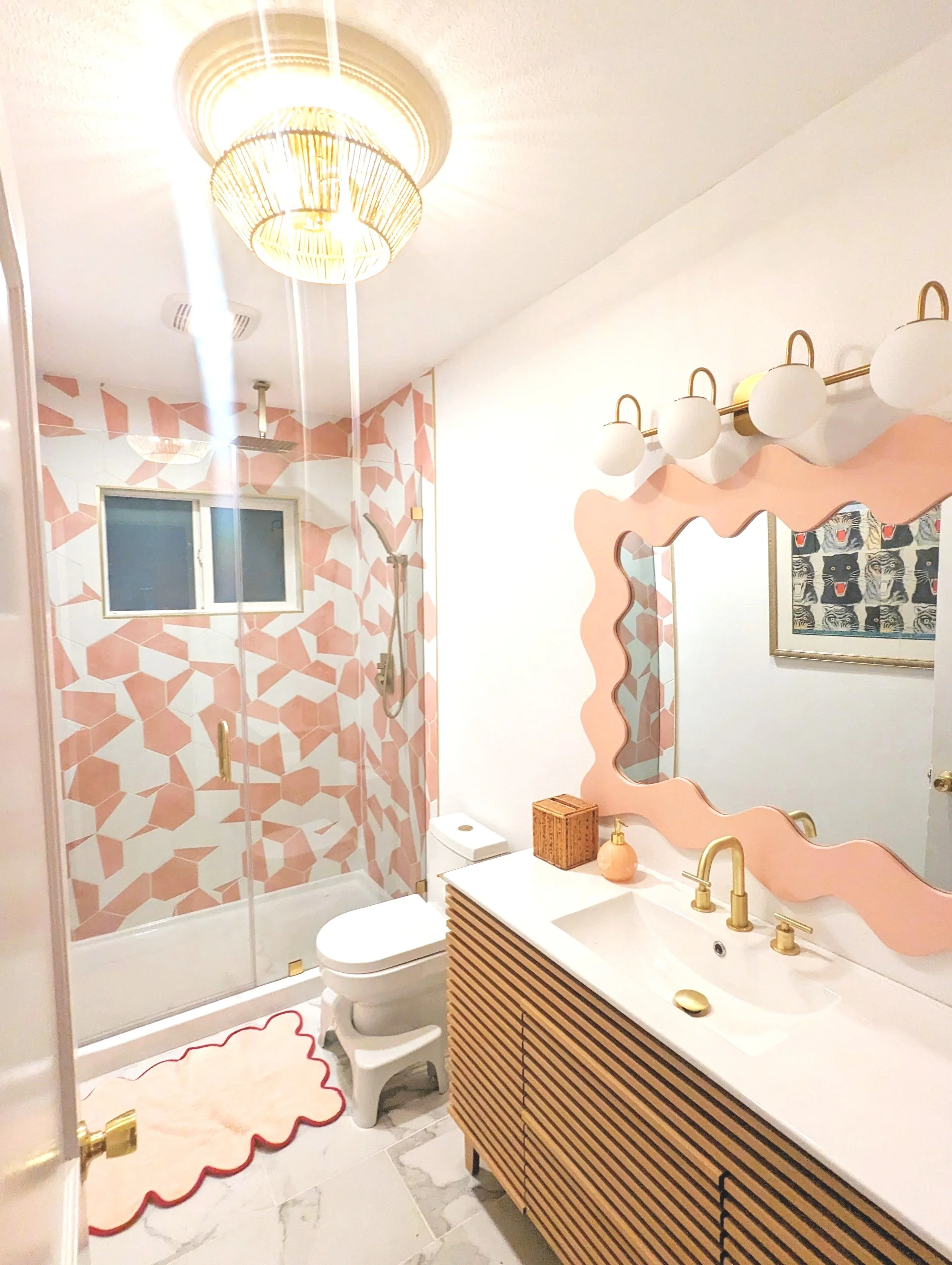Austin Airbnb bathroom featuring a pink mural, custom wavy wood mirror, and eclectic vintage decor by Tola Home.