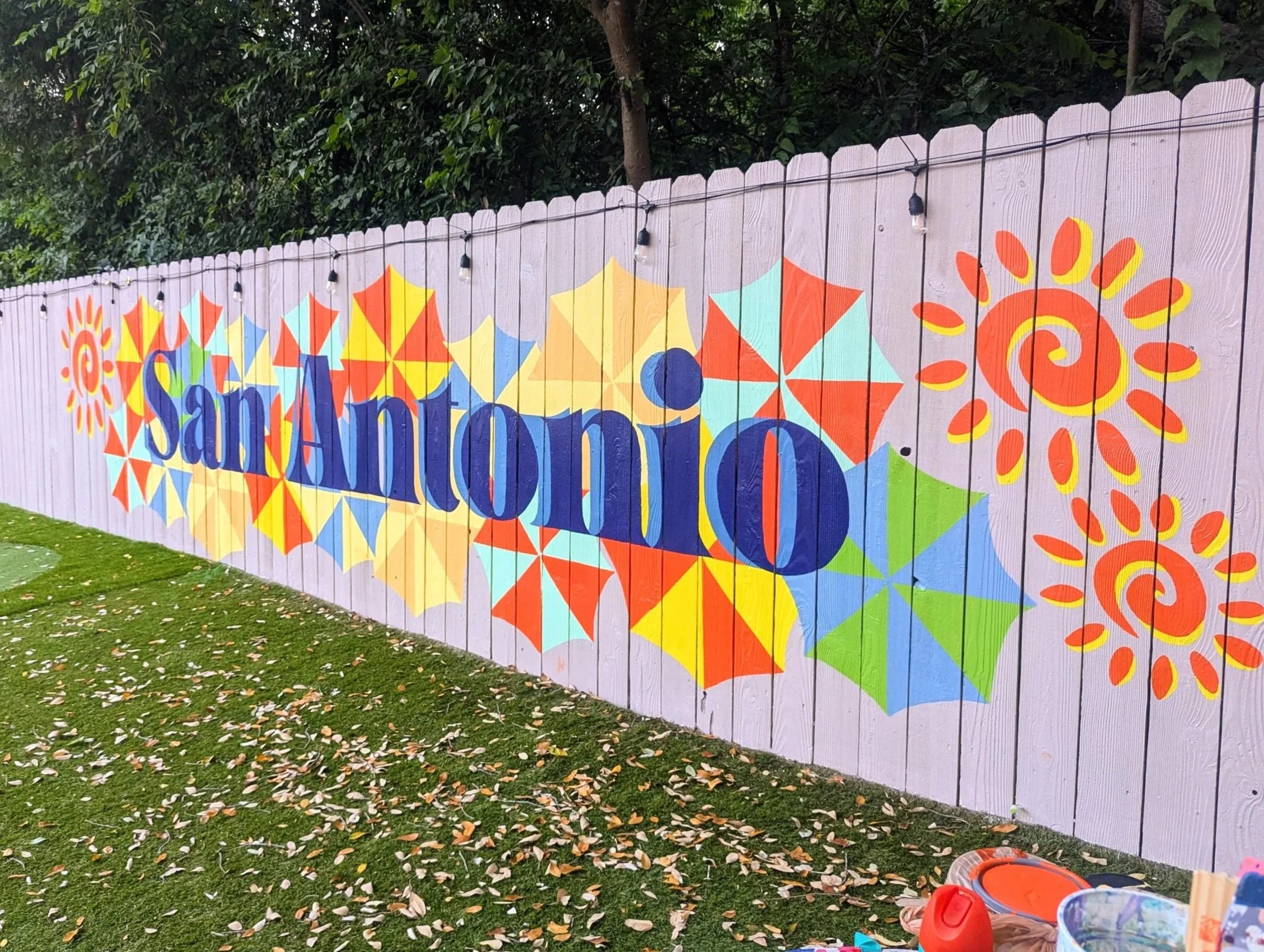 Colorful San Antonio exterior mural with blue lettering and painted fiesta umbrellas inspired by the San Antonio River Walk.