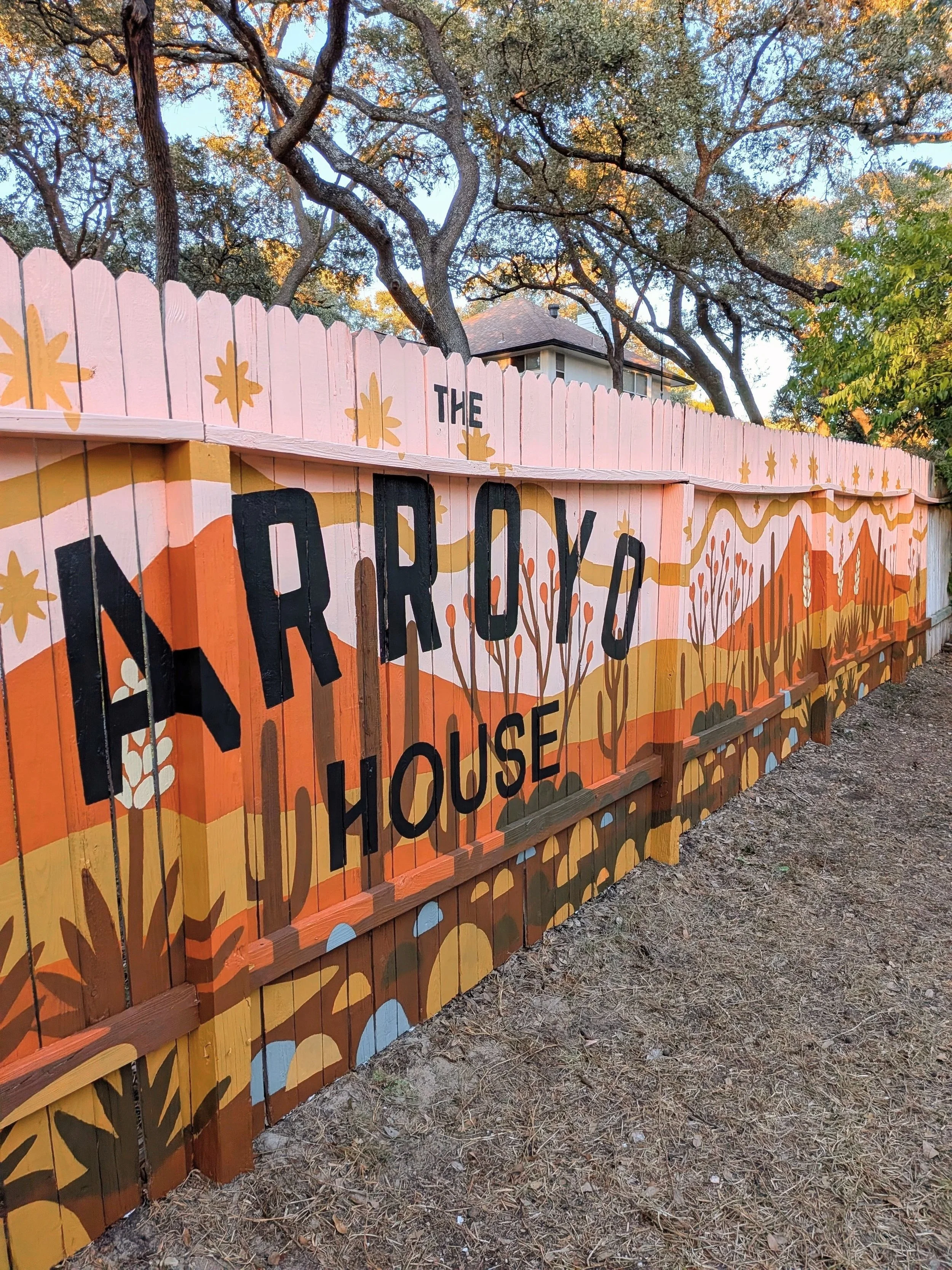 San Antonio short-term rental featuring a 60-foot exterior fence mural with a pink and earth-toned desert landscape and Arroyo House branding.