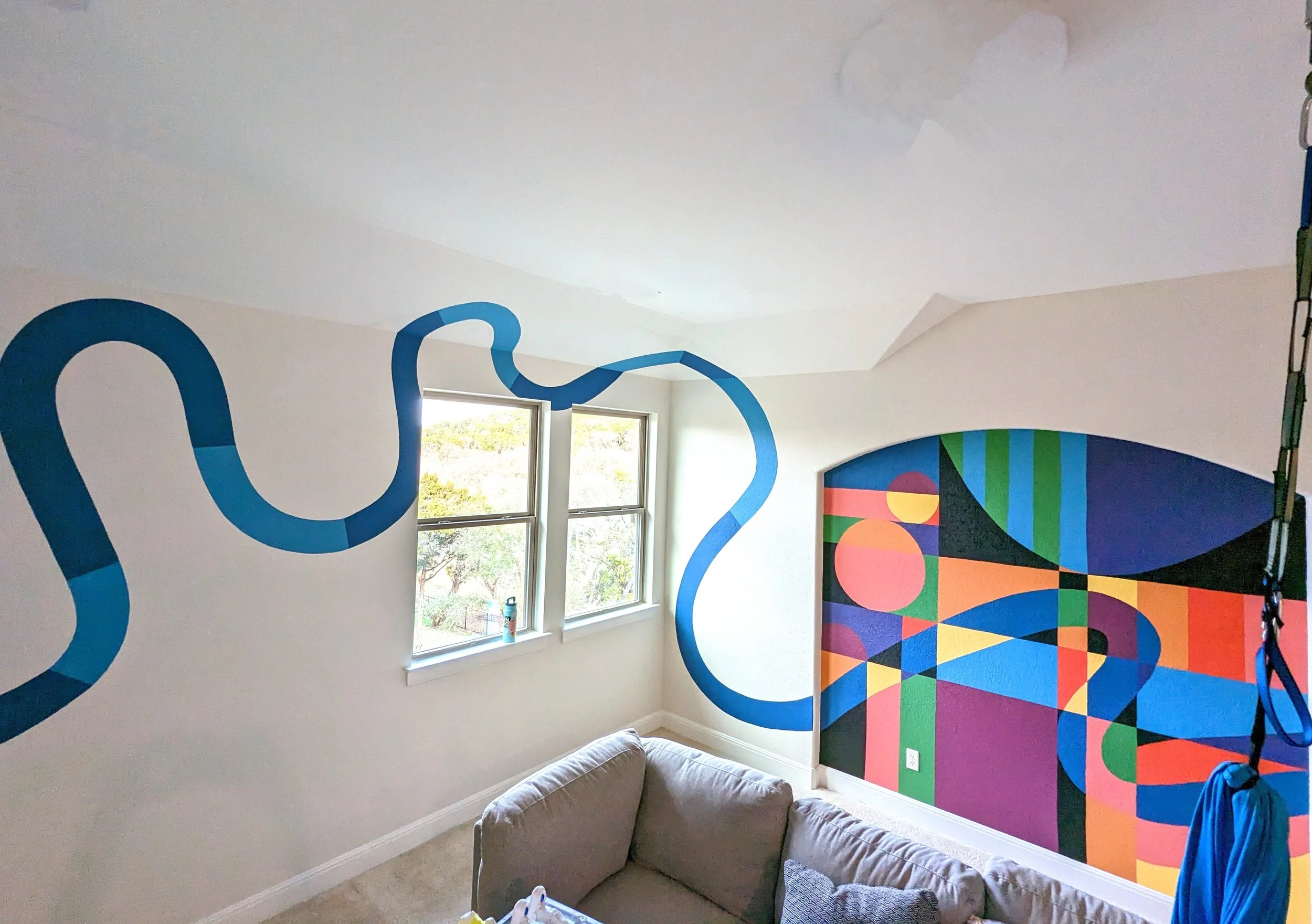 Colorful geometric playroom mural in Leander, Texas wrapping around a corner wall with bold arches and geometric shapes.