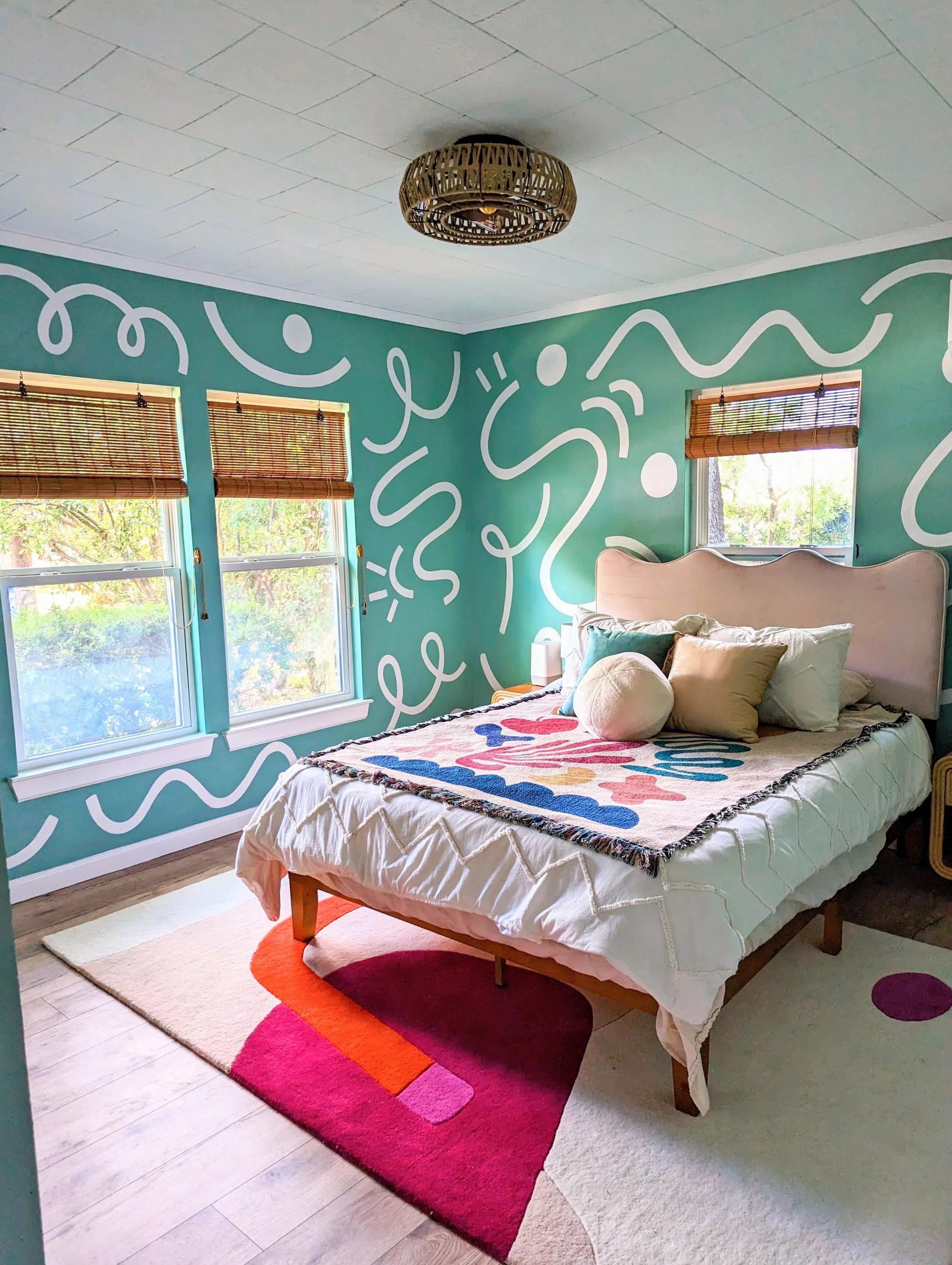 Austin Airbnb bedroom featuring a green abstract mural, vintage furnishings, eclectic decor, and original artwork by Tola Home.