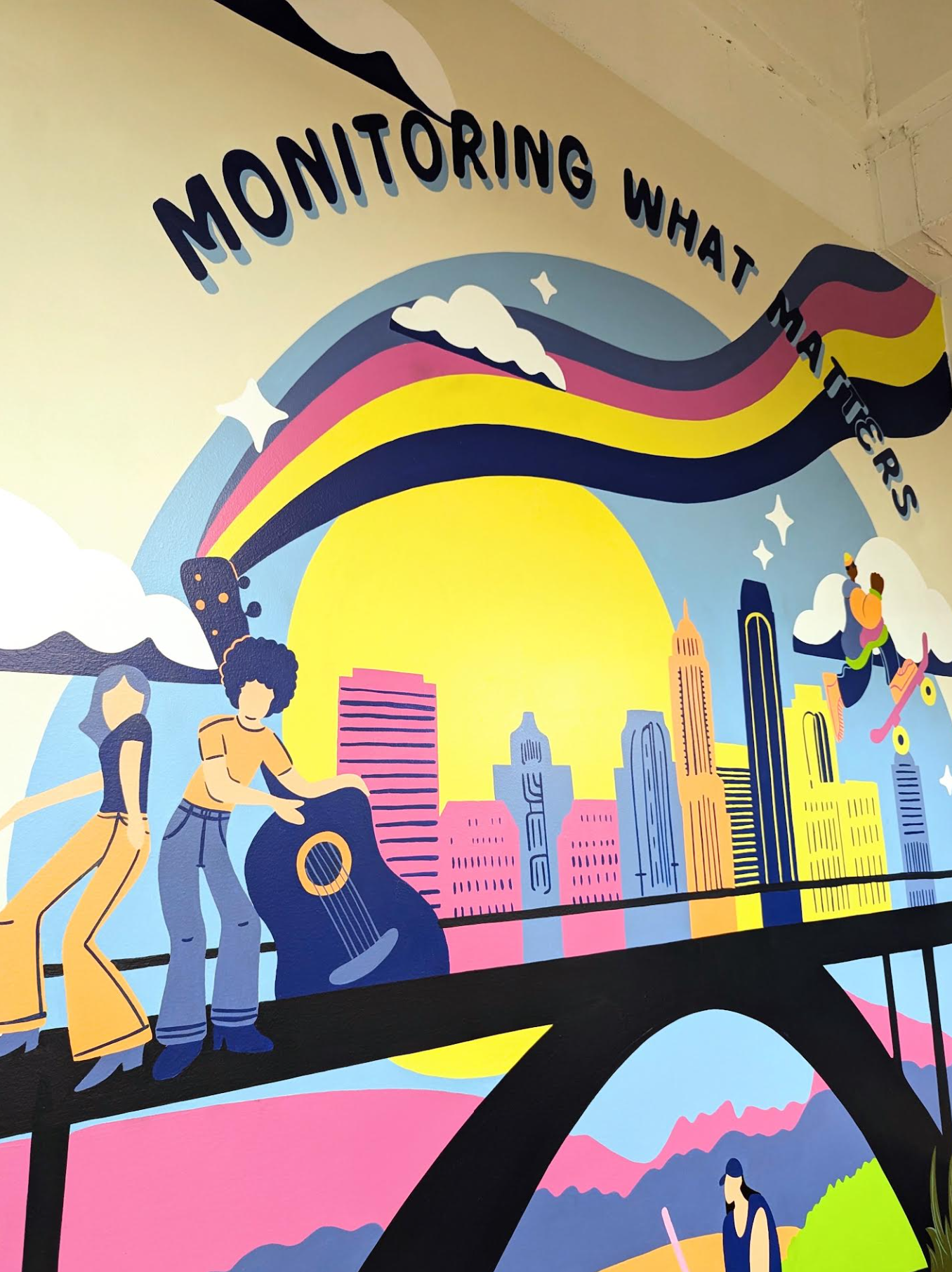 LogicMonitor office mural in downtown Austin featuring the Austin skyline, rainbow, illustrated figures, and outdoor activities in the company's brand colors.