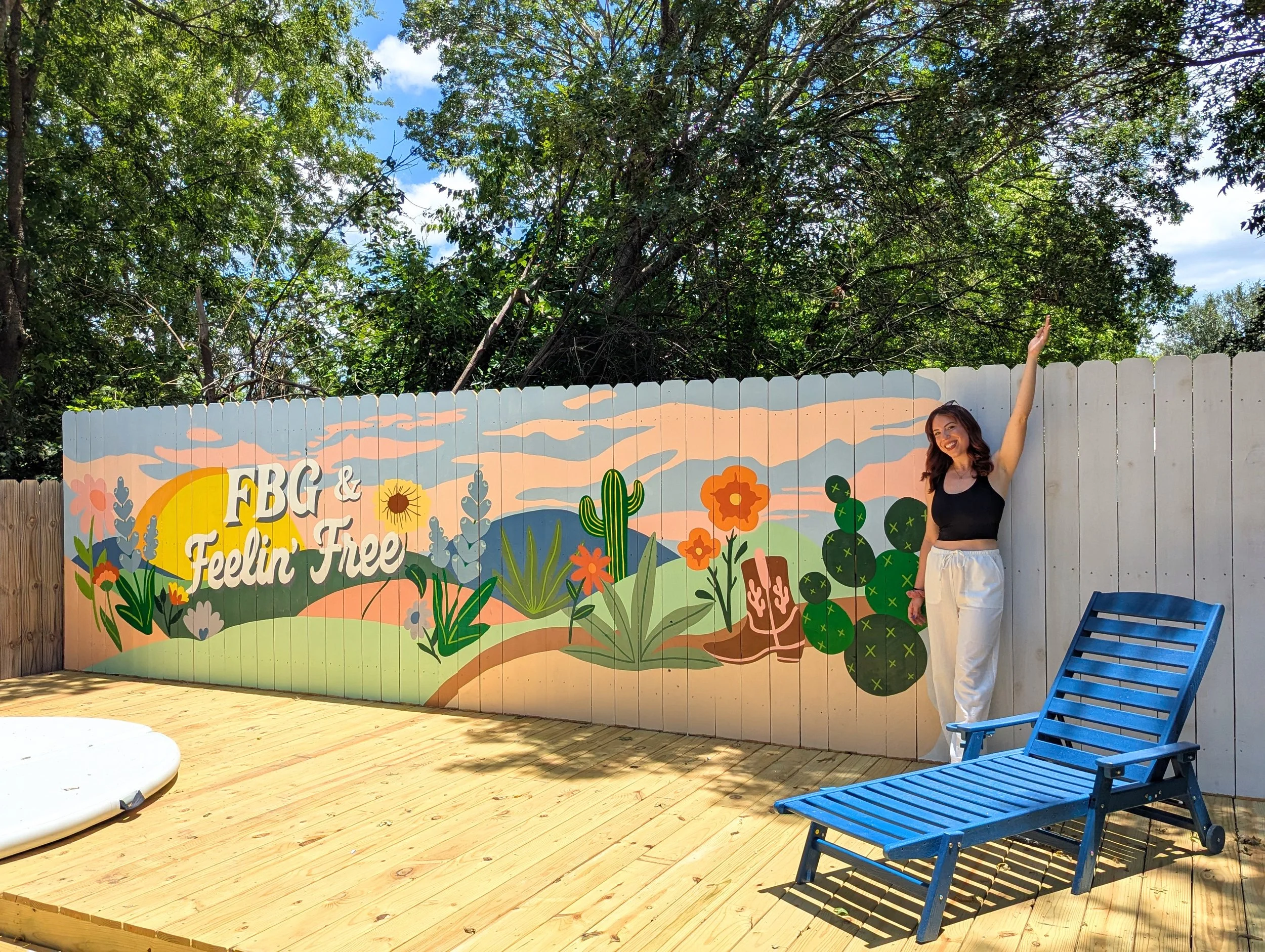 Fredericksburg, Texas short-term rental fence mural featuring painted wildflowers, native plants, and a sunset sky.