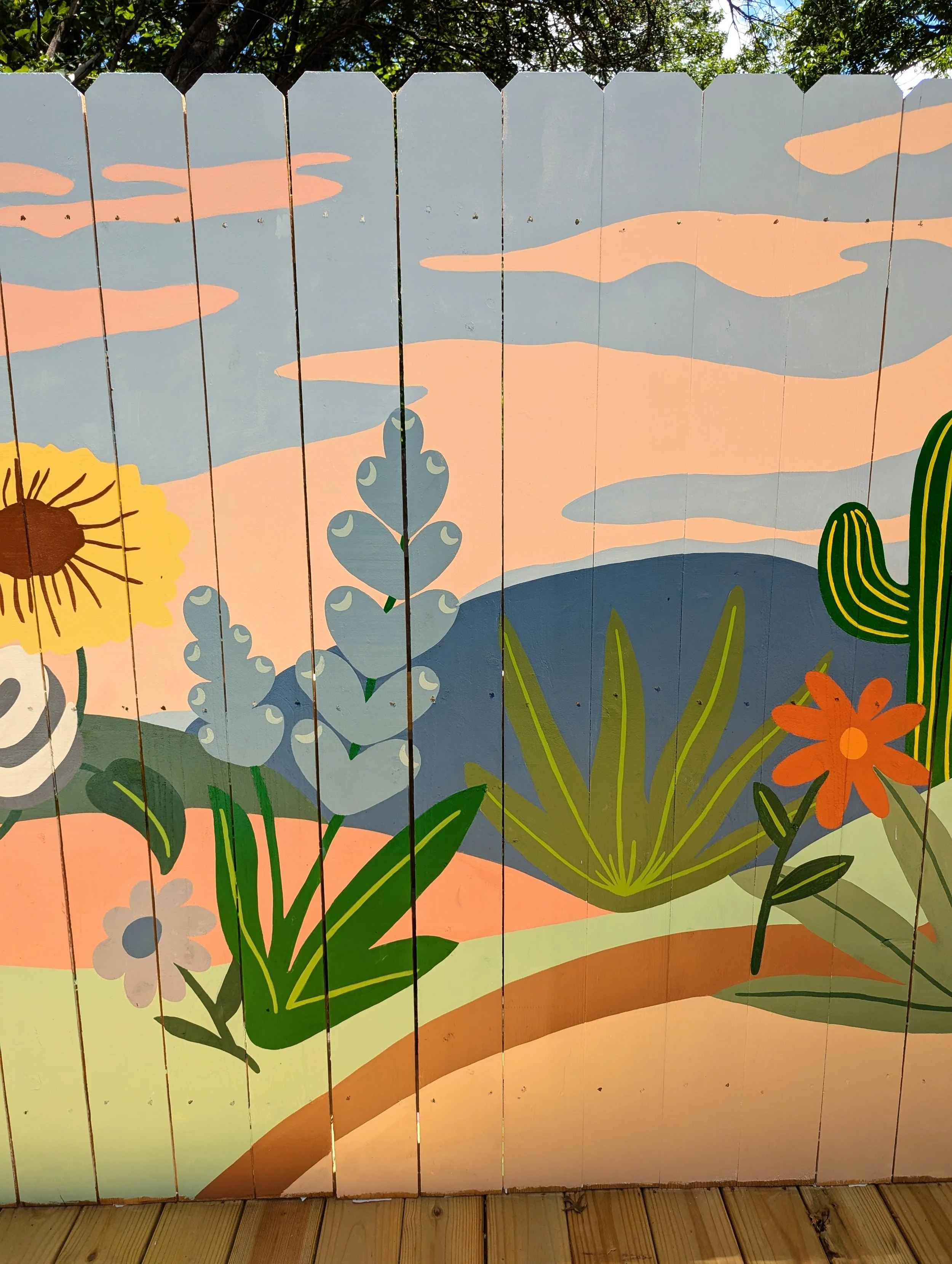 Fredericksburg, Texas short-term rental with a colorful outdoor fence mural featuring wildflowers and Texas Hill Country-inspired artwork including bluebonnets, sunflowers, cactus, and indian paintbrushes.