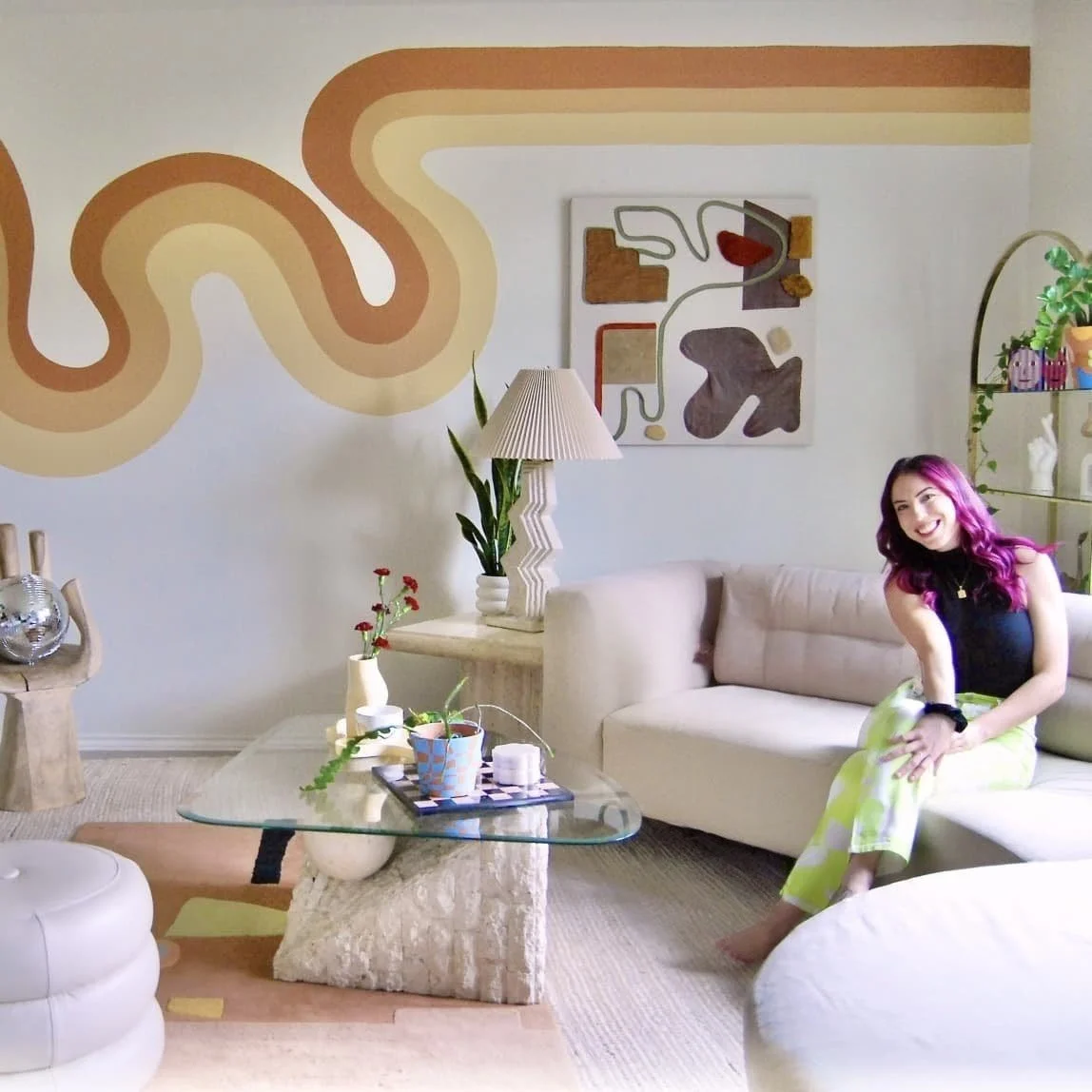 Artist and Tola Home founder in her colorful Buda, Texas living room, surrounded by original murals, vintage finds, and eclectic decor.