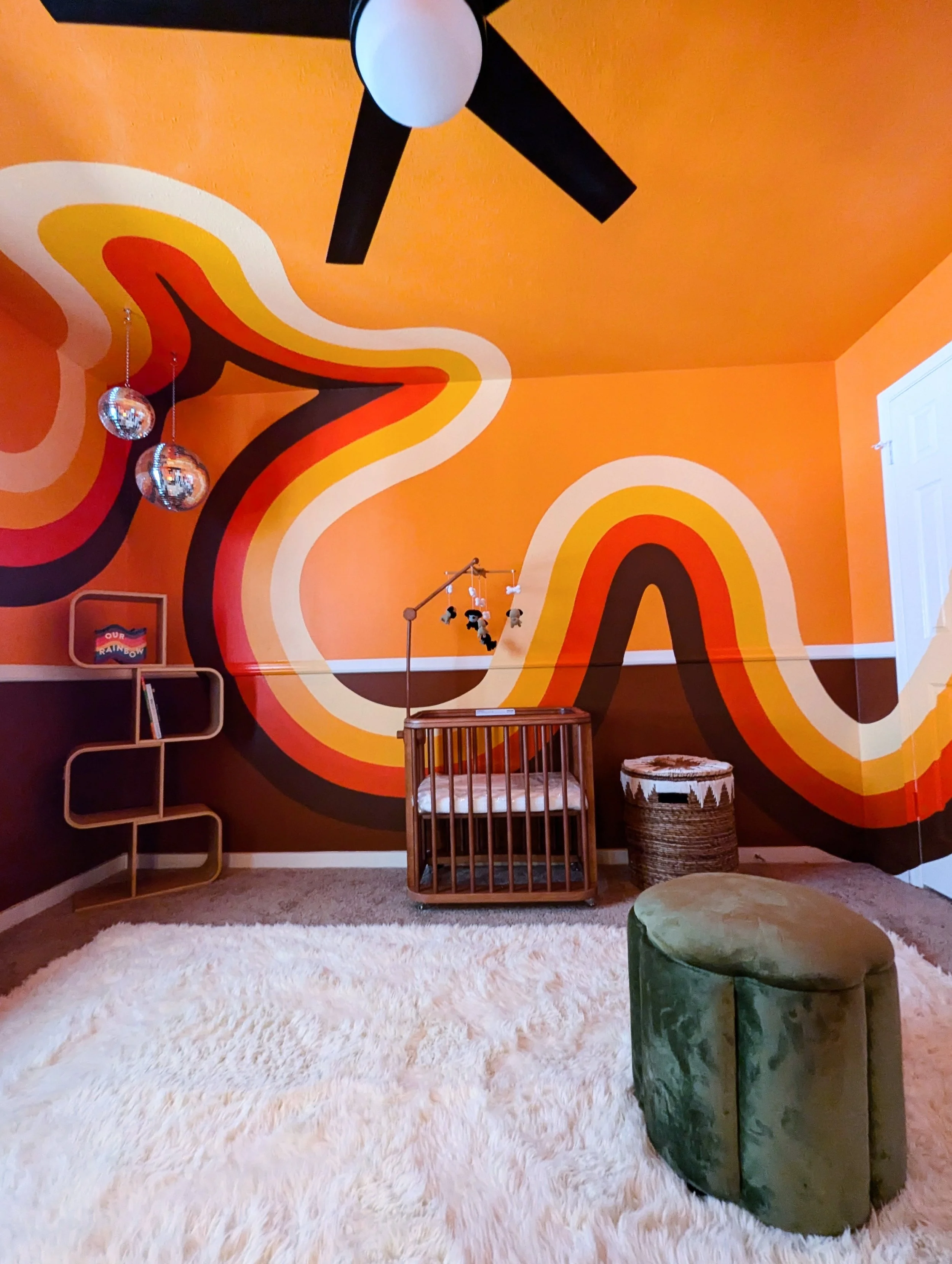 Retro nursery mural in Austin featuring orange waves painted across the walls, ceiling, doors, and trim.