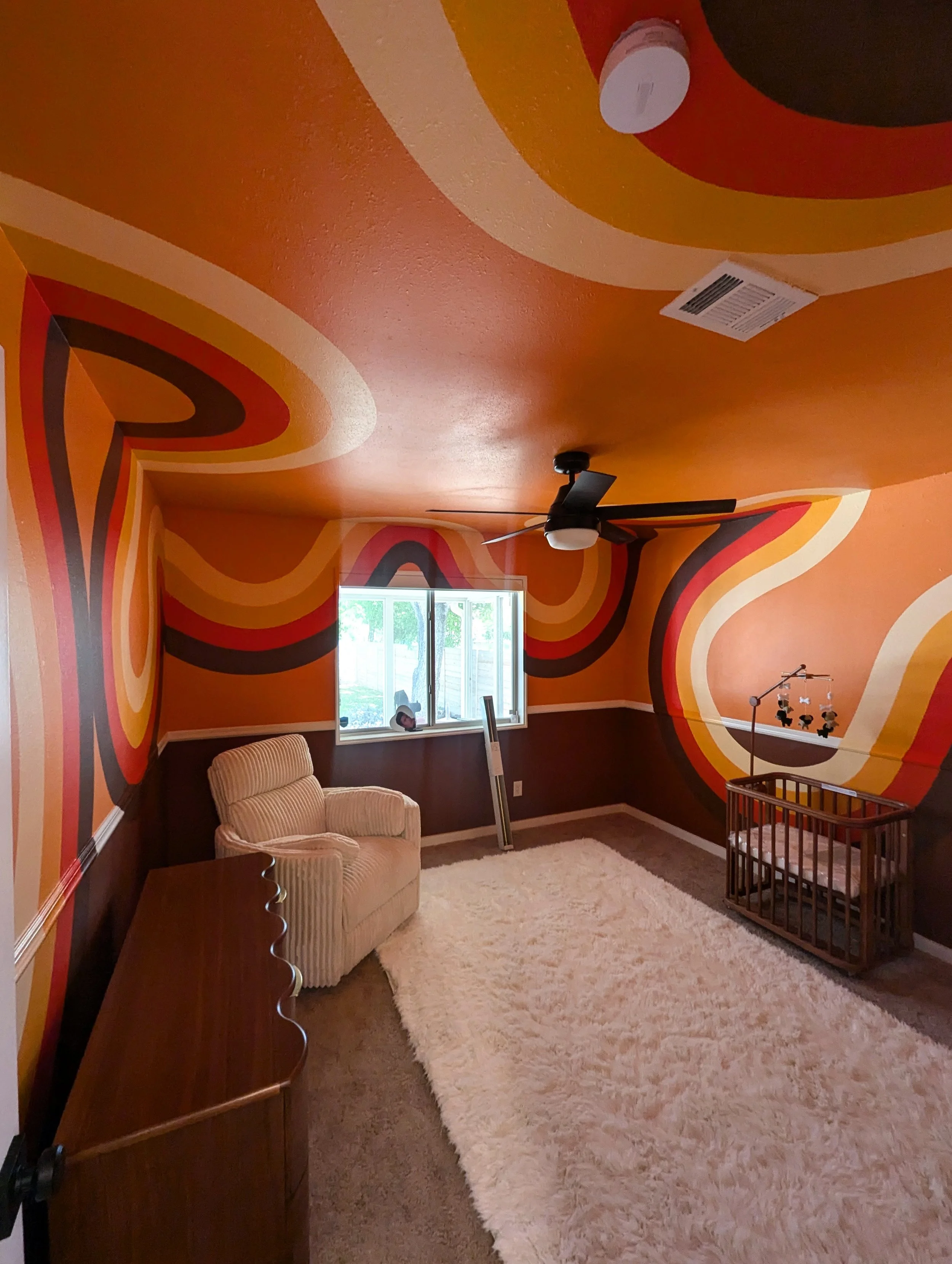 Retro orange nursery mural in Austin with color-drenched walls, painted ceiling, doors, and trim.