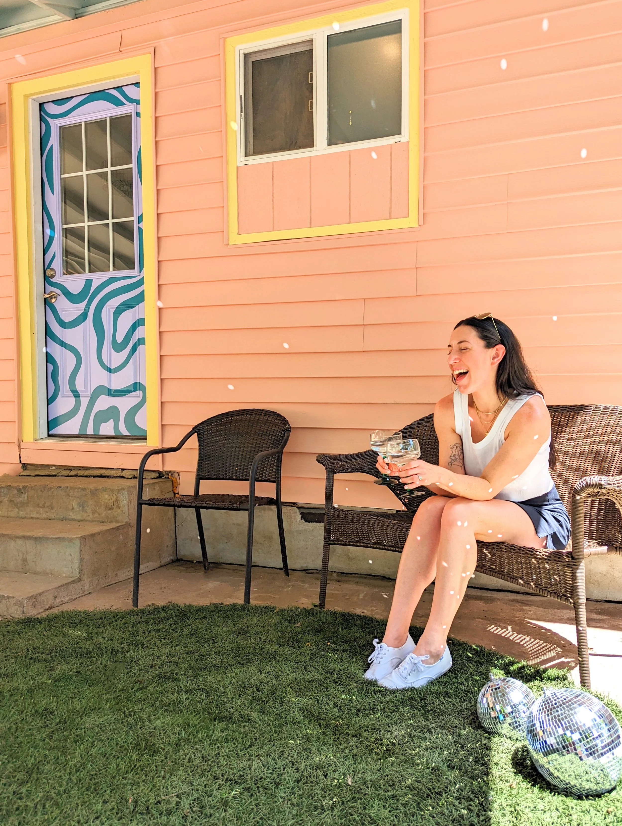 The Howdy Hideaway Austin Airbnb backyard featuring a painted pink exterior, purple squiggly abstract mural, and colorful outdoor details.