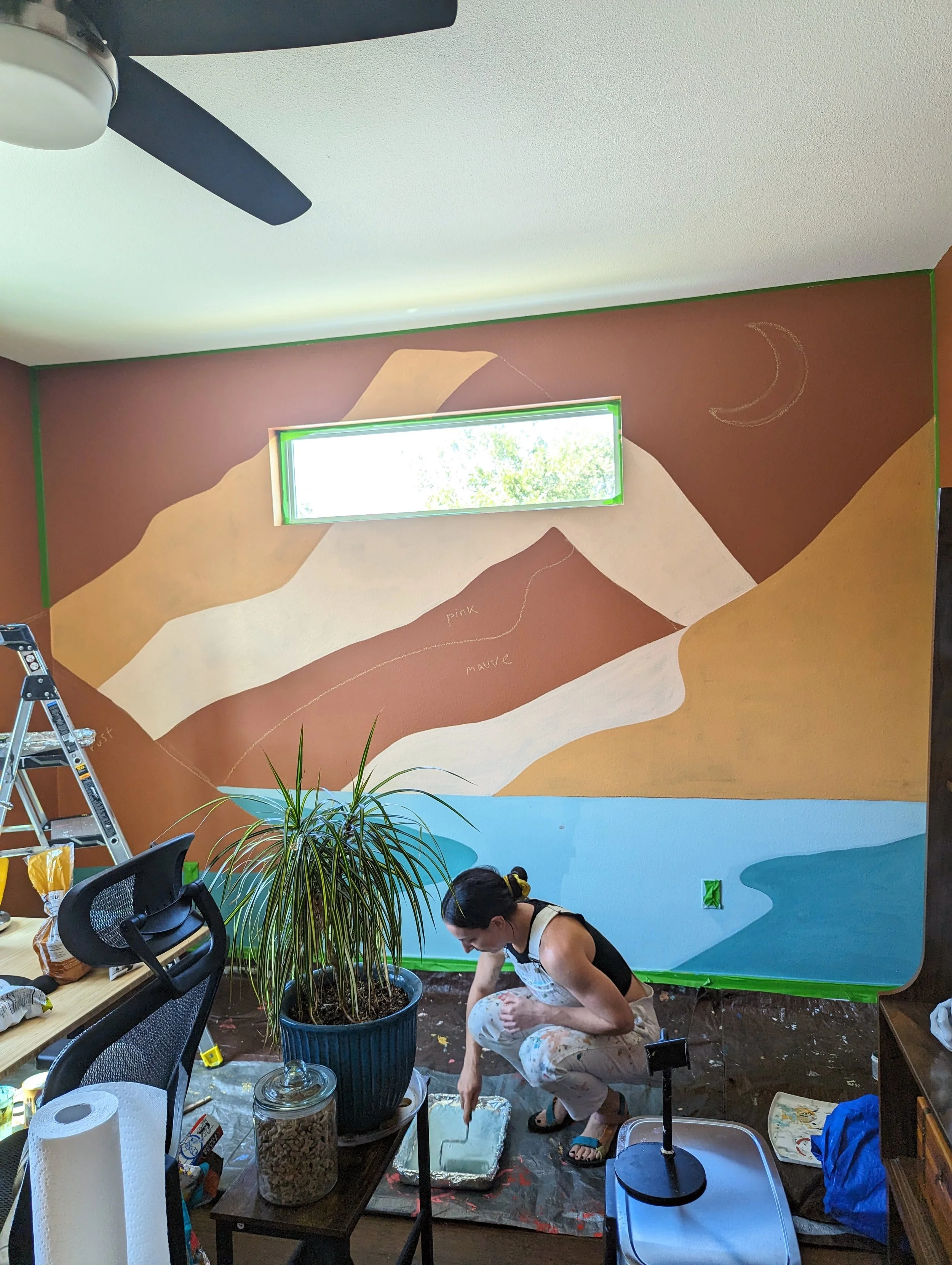 Austin, Texas nursery mural featuring a mountain landscape with a crescent moon and stars, shown while the artist paints the room.