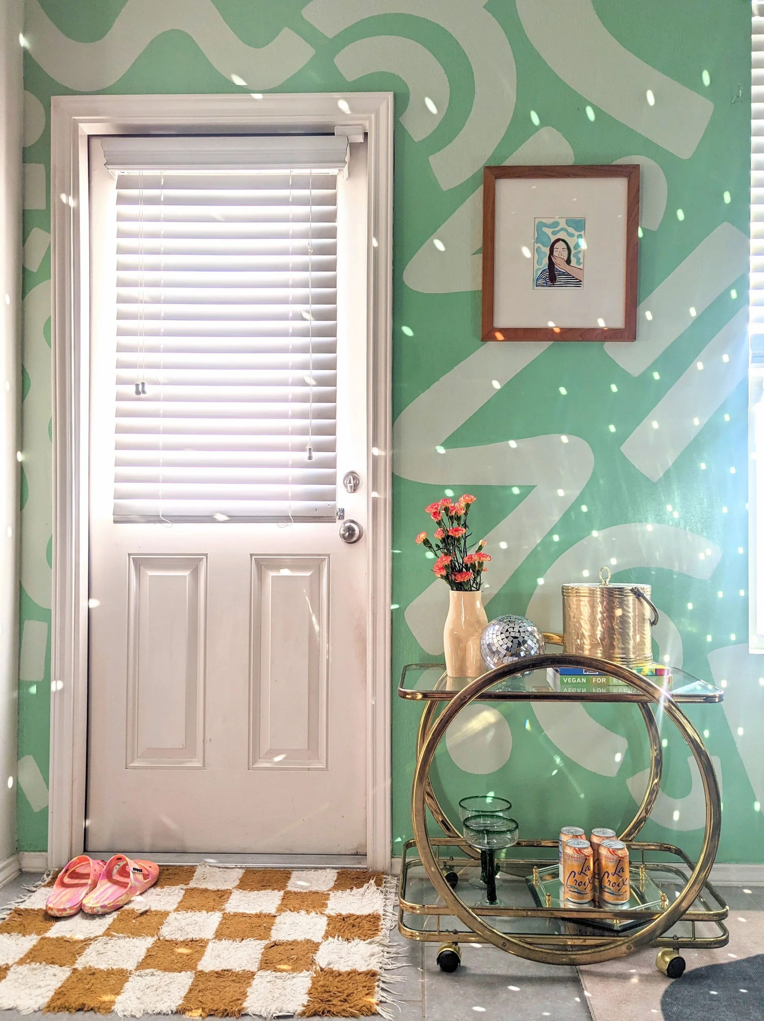 Green abstract dining room in a Buda, Texas home featuring an organic shape mural, vintage bar cart, and eclectic decor.