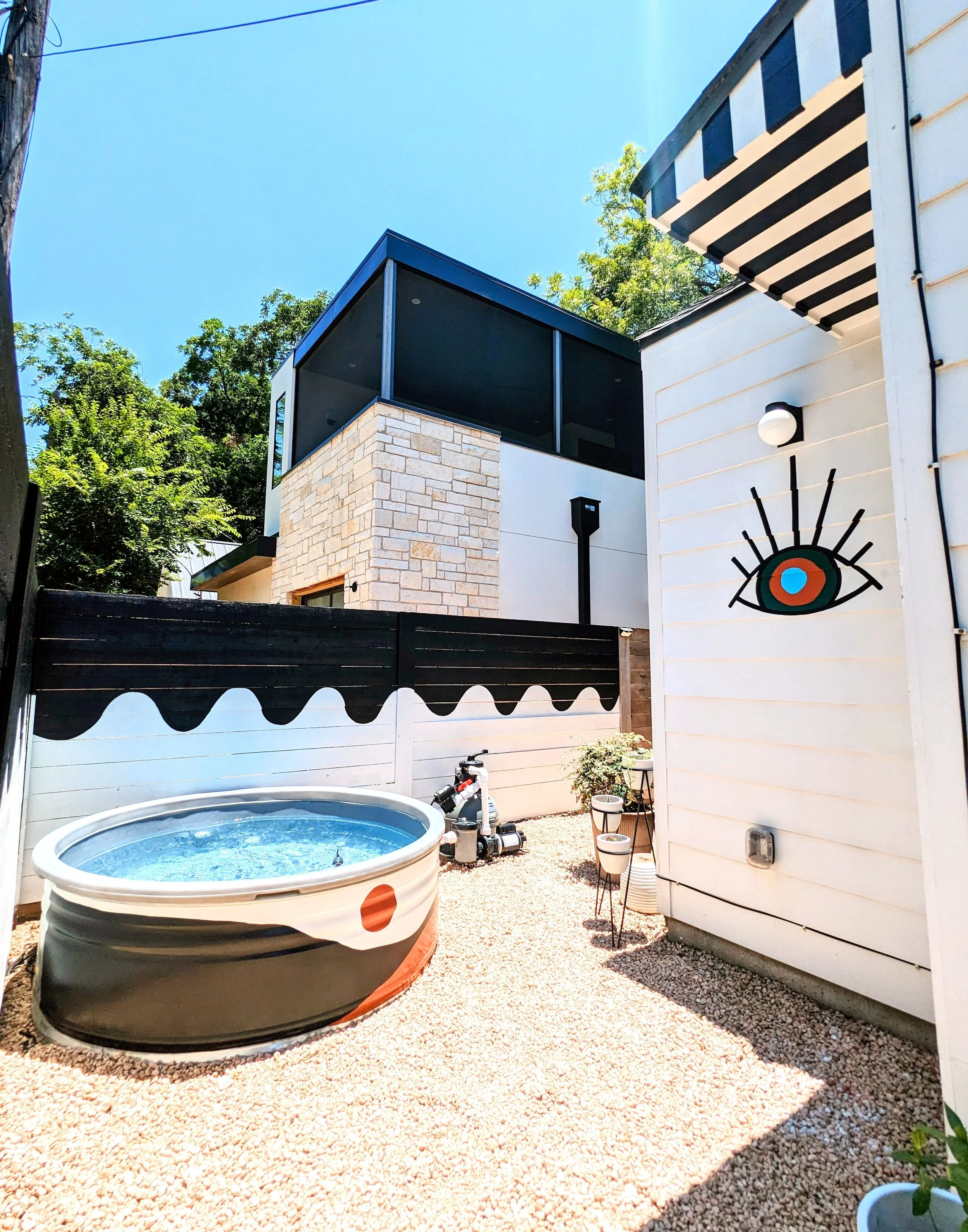 East Austin backyard mural featuring a painted fence, cowboy pool, awning, and colorful artwork inspired by El Rey Court in Santa Fe.