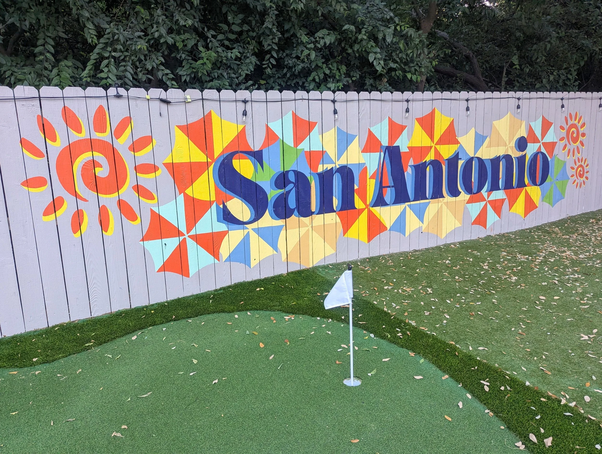 San Antonio short-term rental exterior fence mural featuring colorful fiesta colors and riverwalk umbrellas. 