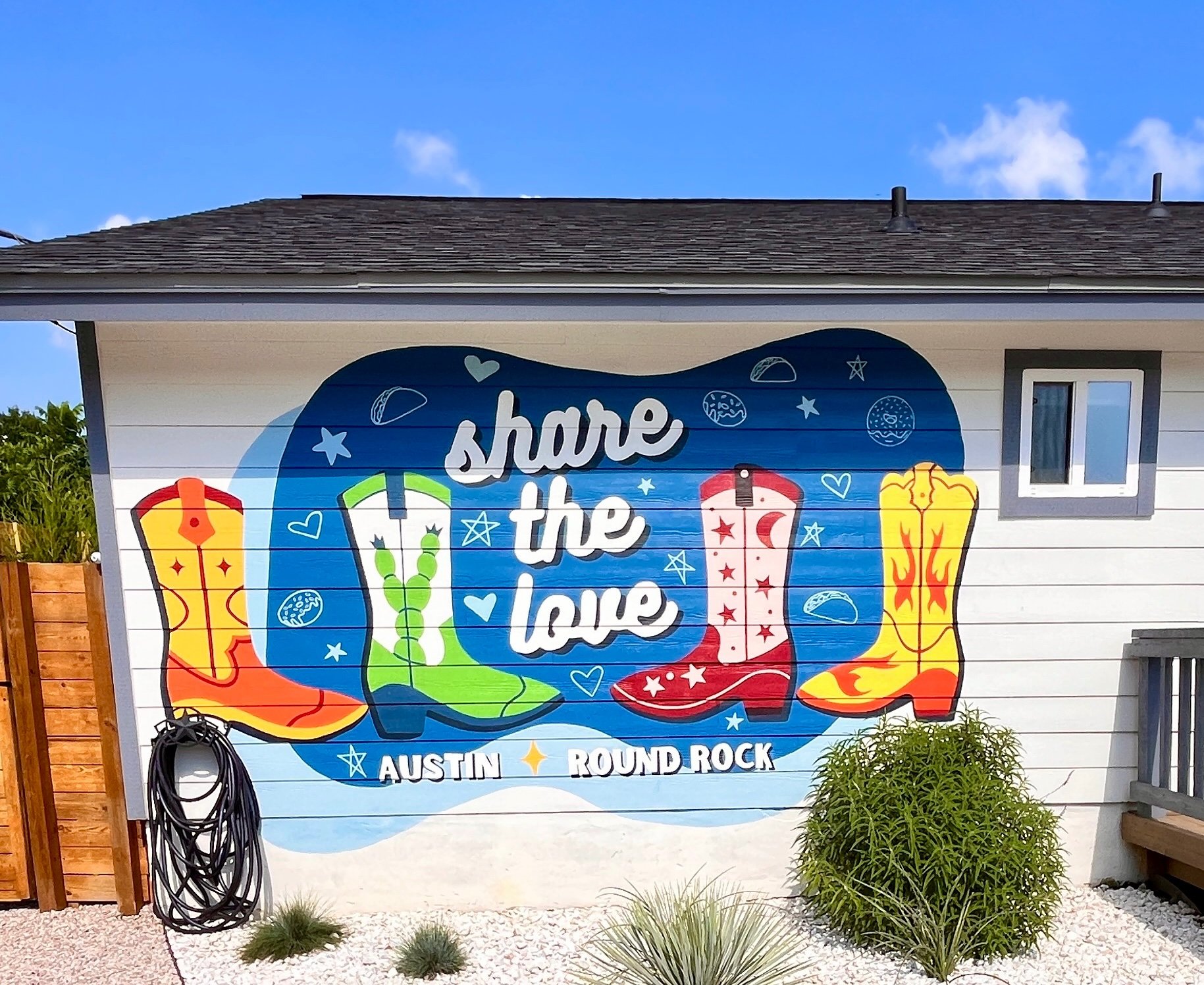 A painted mural on the side of a house reads 'share the love' and features colorful illustrations of flip-flops, with the location 'Austin Round Rock' at the bottom.