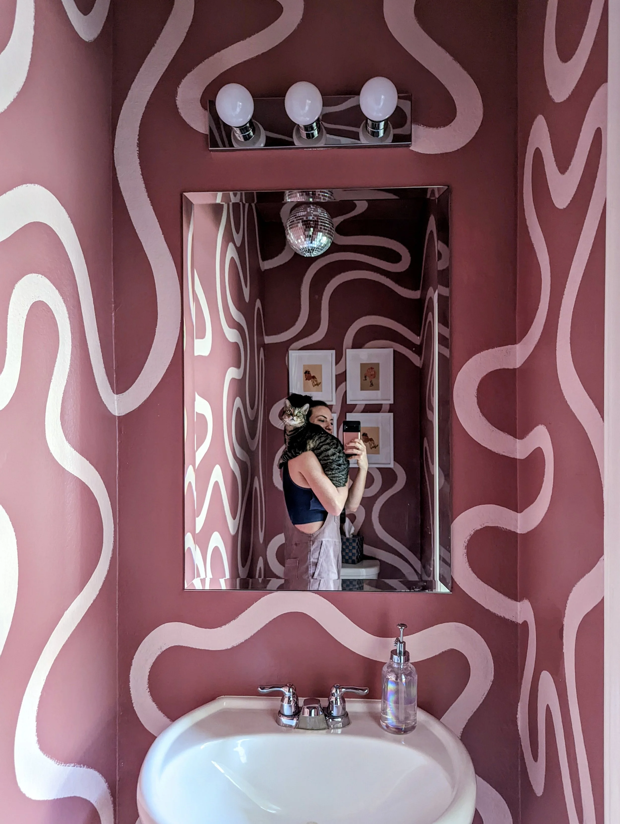 Playful bathroom mural in an Austin-area home with mauve purple and white wavy shapes, featured in Apartment Therapy.