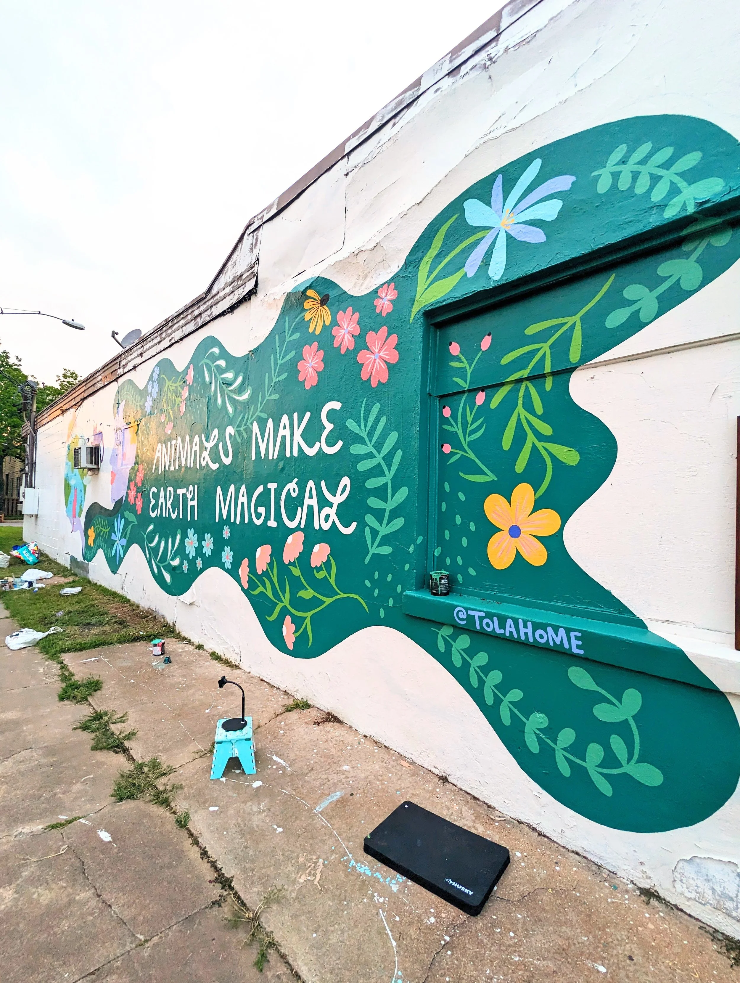 Large-scale exterior mural for Austin Pets Alive! in Austin, Texas featuring animals, flowers, greenery, and the phrase "Animals Make Earth Magical."