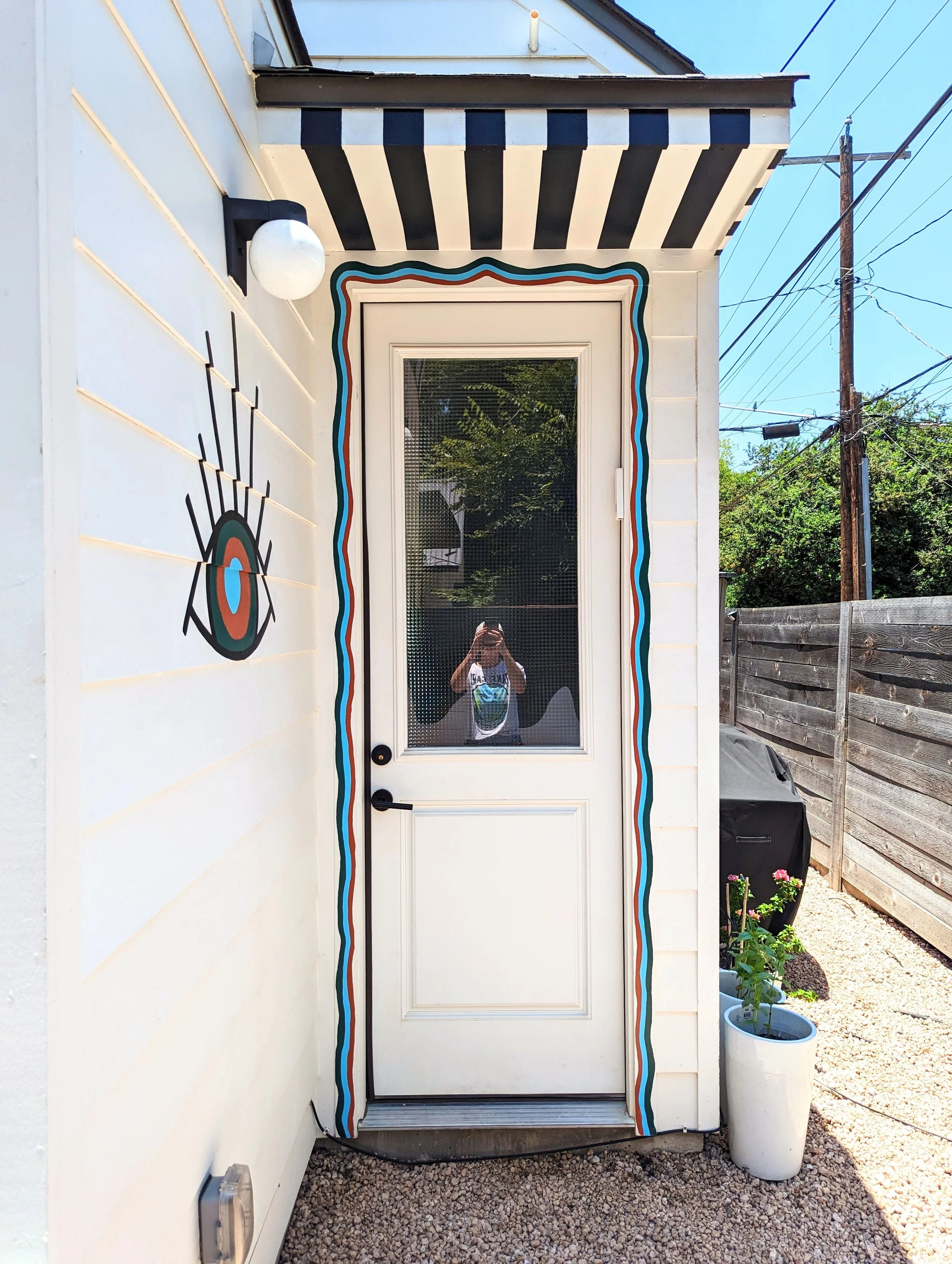 East Austin backyard mural extending across the fence, awning, and side of the house surrounding a painted cowboy pool.