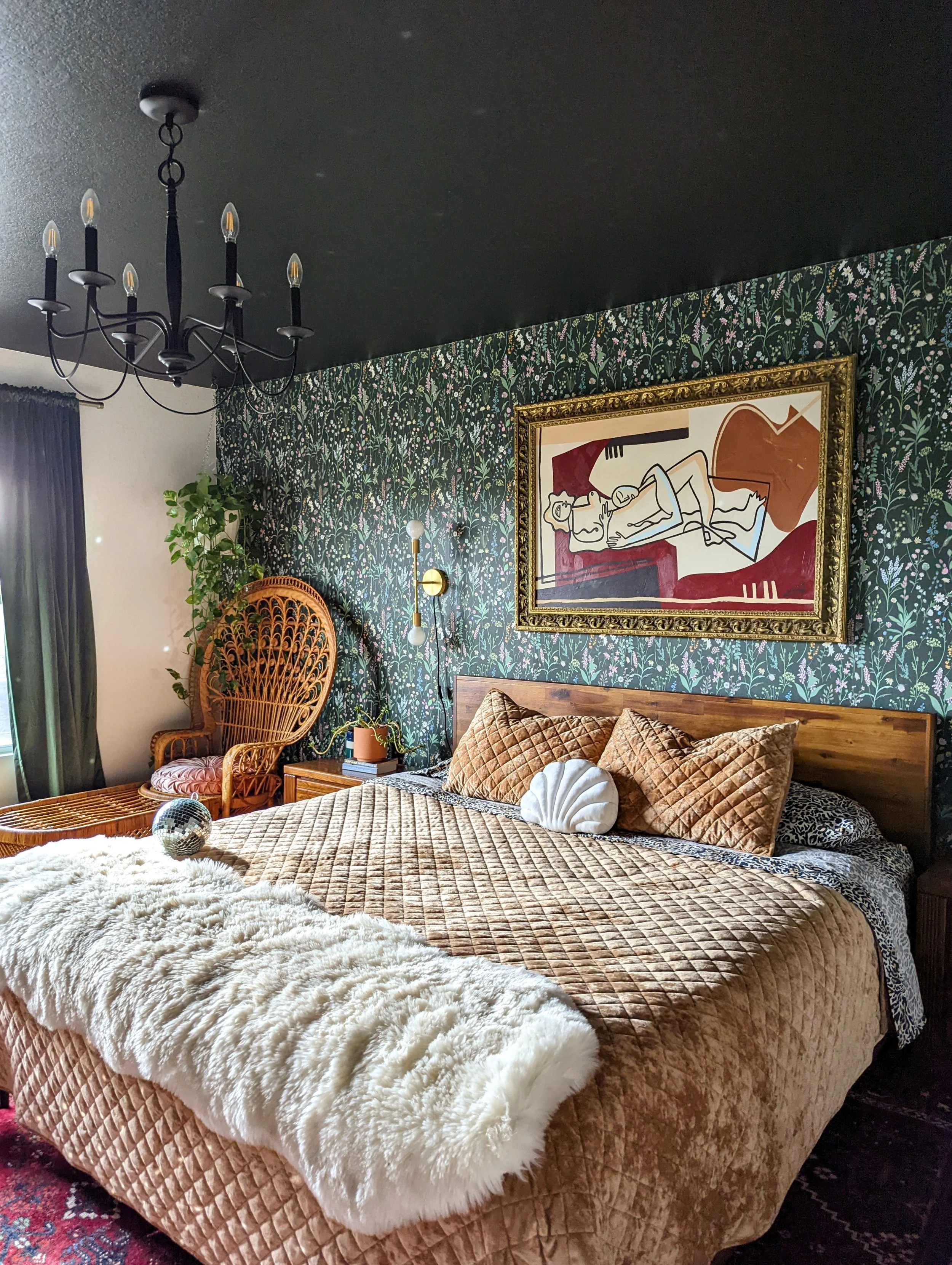 Moody bedroom in an Austin-area home featuring vintage furnishings, floral wallpaper, layered textiles, and a dark ceiling, featured in Apartment Therapy.