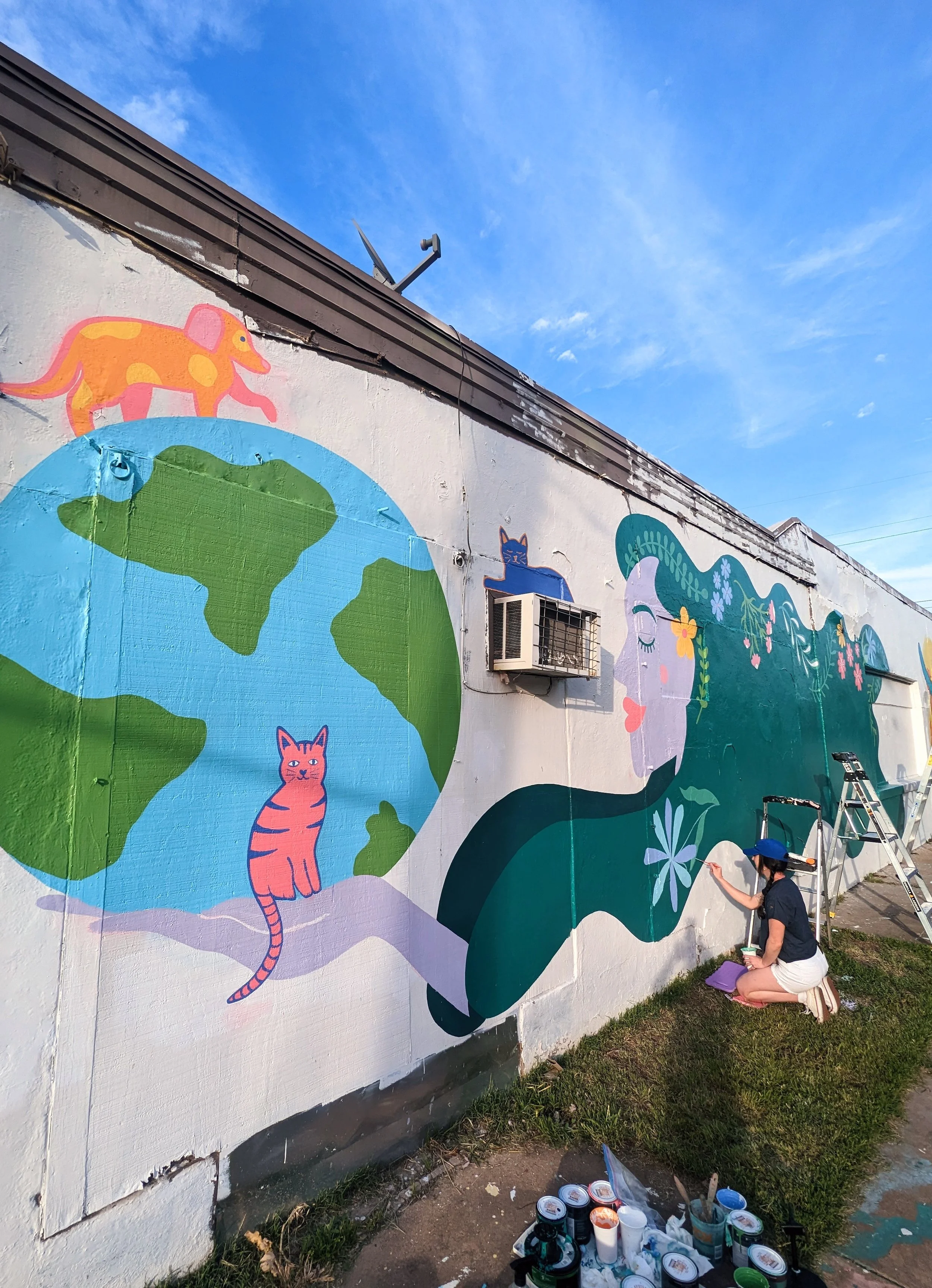 Austin Pets Alive! mural being painted on a large exterior wall in Austin, Texas, featuring animals and colorful abstract shapes.