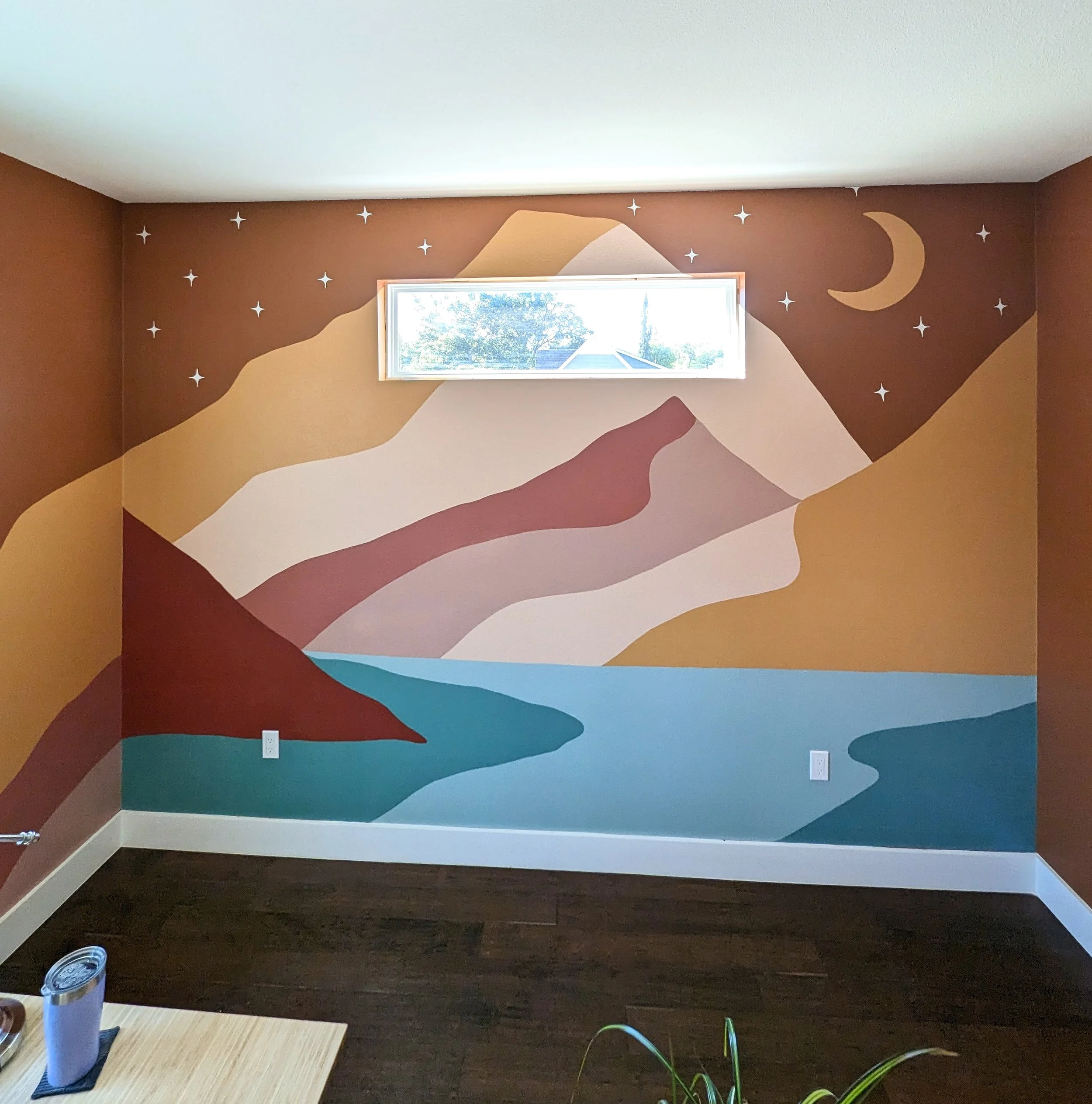 Mountain landscape nursery mural in Austin, Texas featuring layered hills, a crescent moon, stars, and whimsical sparkles.