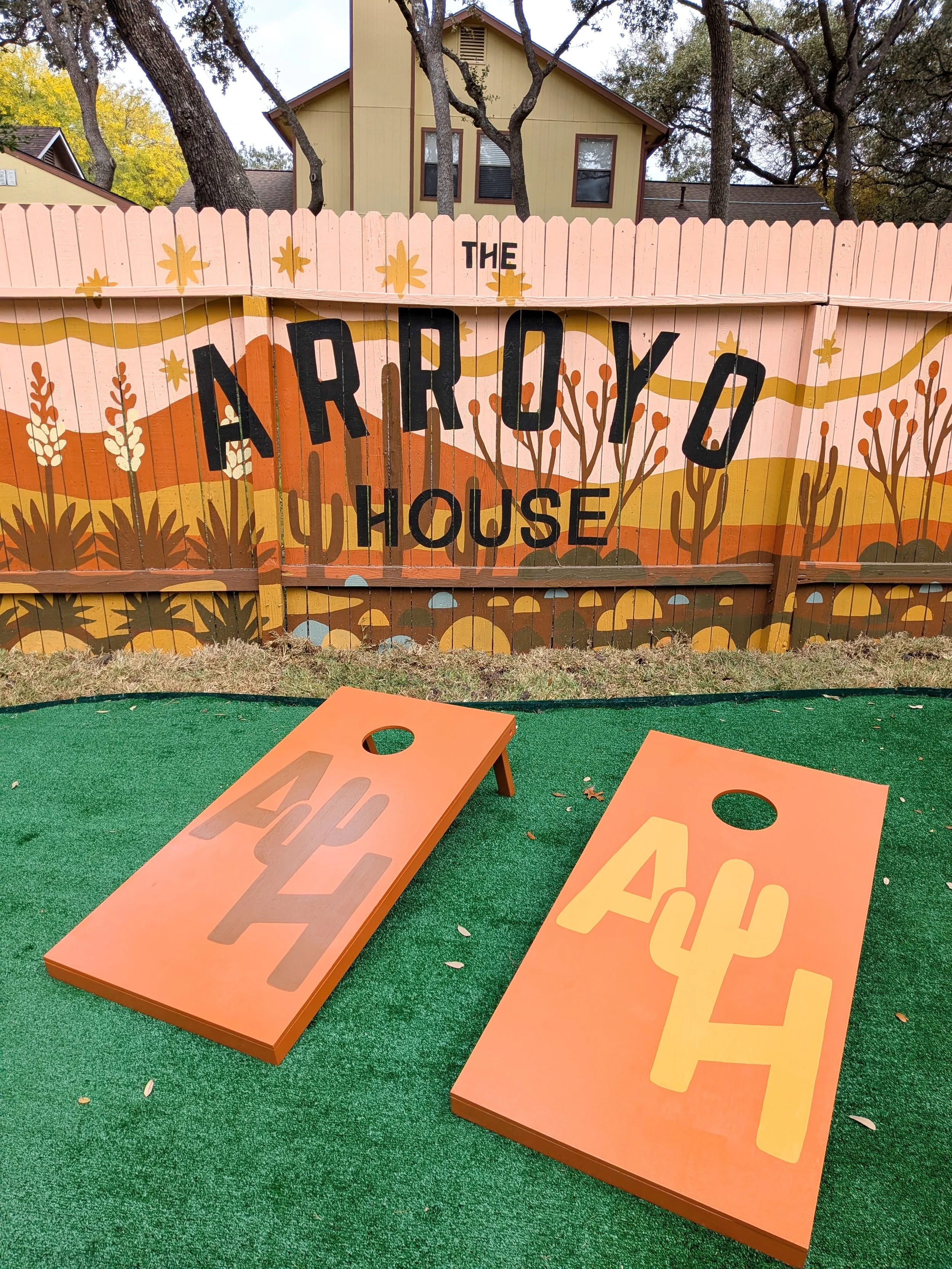 Short-term rental mural in San Antonio featuring a desert-inspired painted fence, custom cornhole boards, and colorful western artwork.