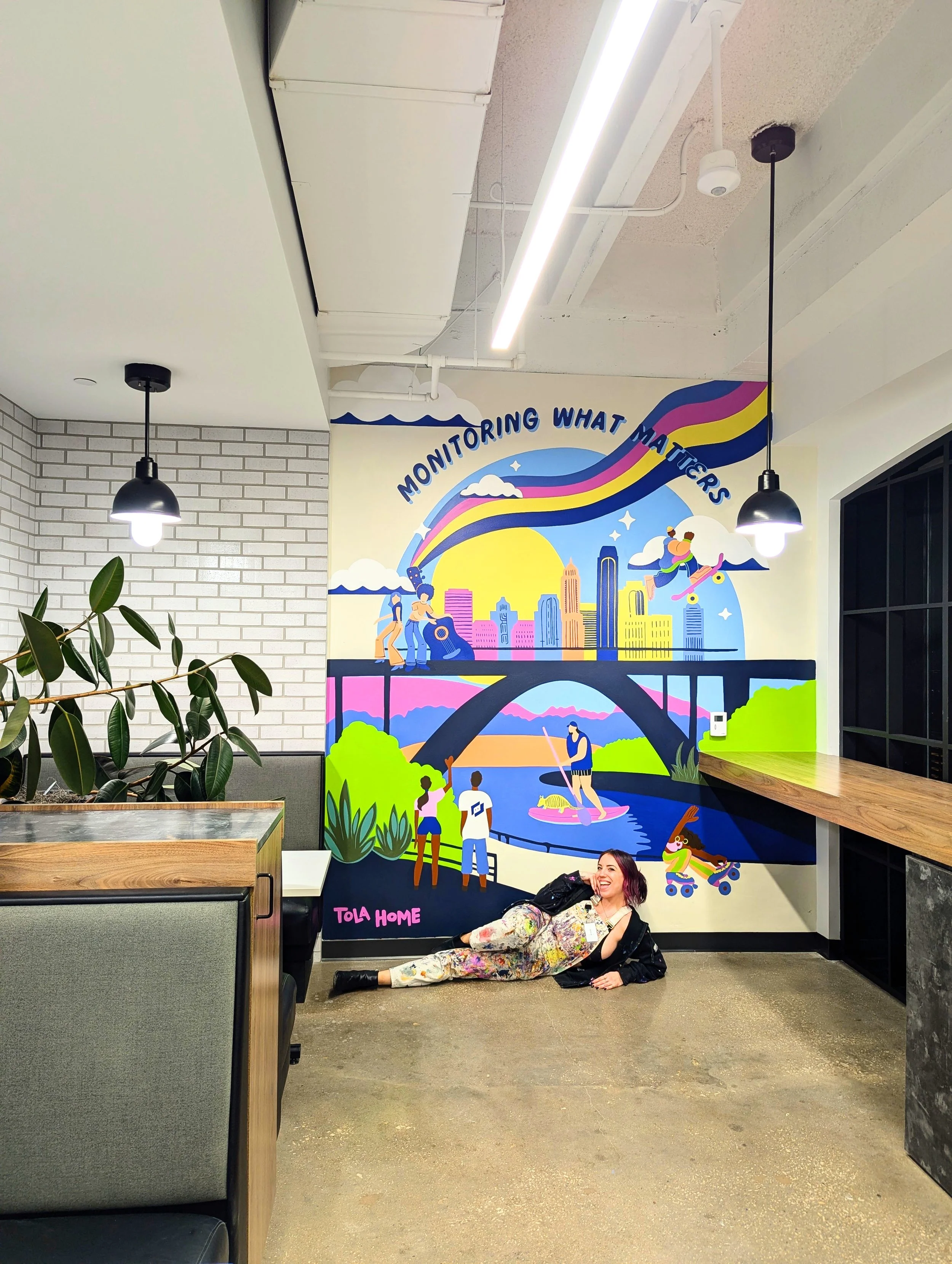 LogicMonitor office mural in downtown Austin featuring Austin-inspired artwork, a colorful cityscape, rainbow, and illustrated figures.