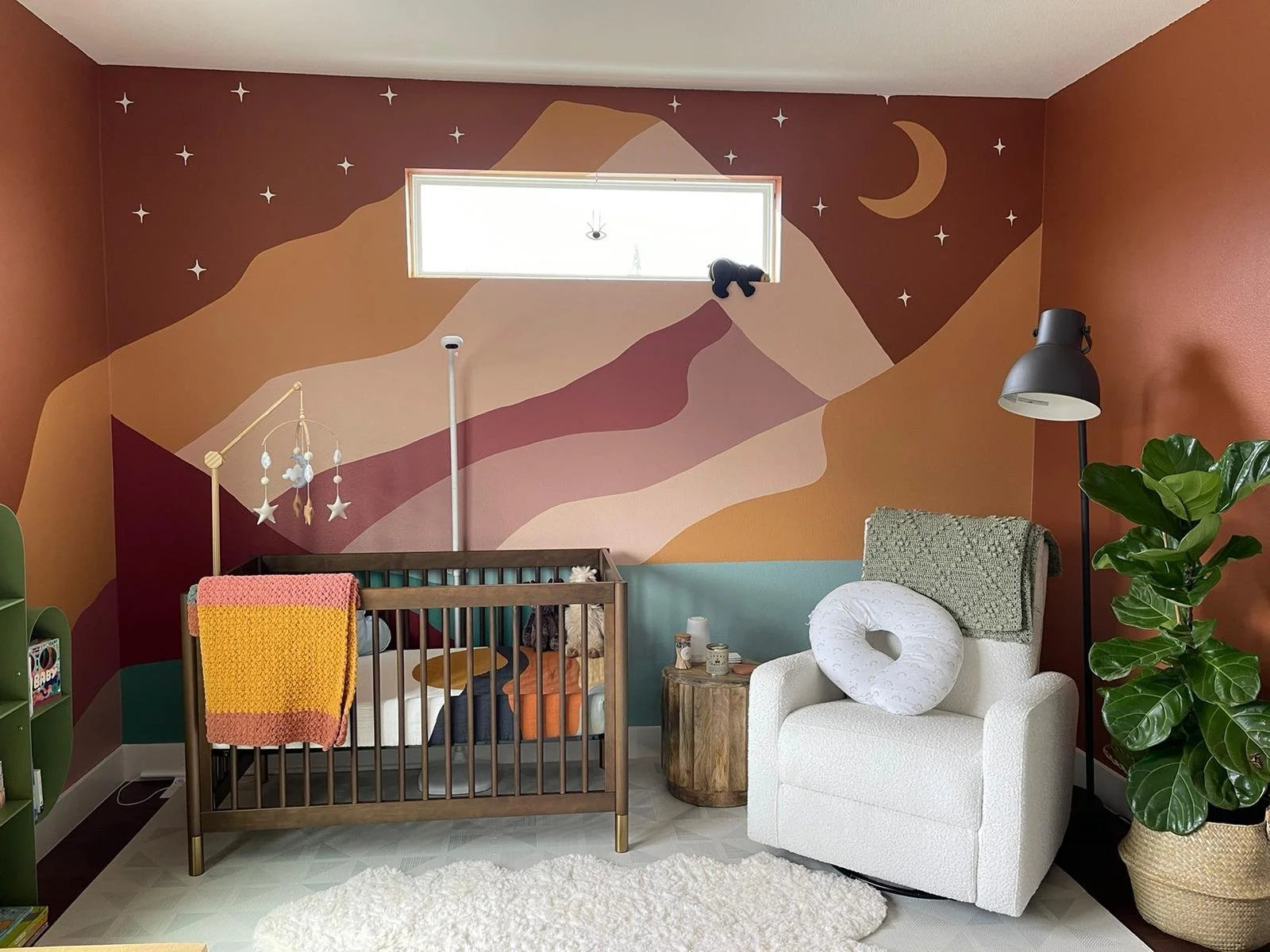 Mountain nursery mural in Austin, Texas featuring layered mountain shapes, earthy colors, stars, and a crescent moon.