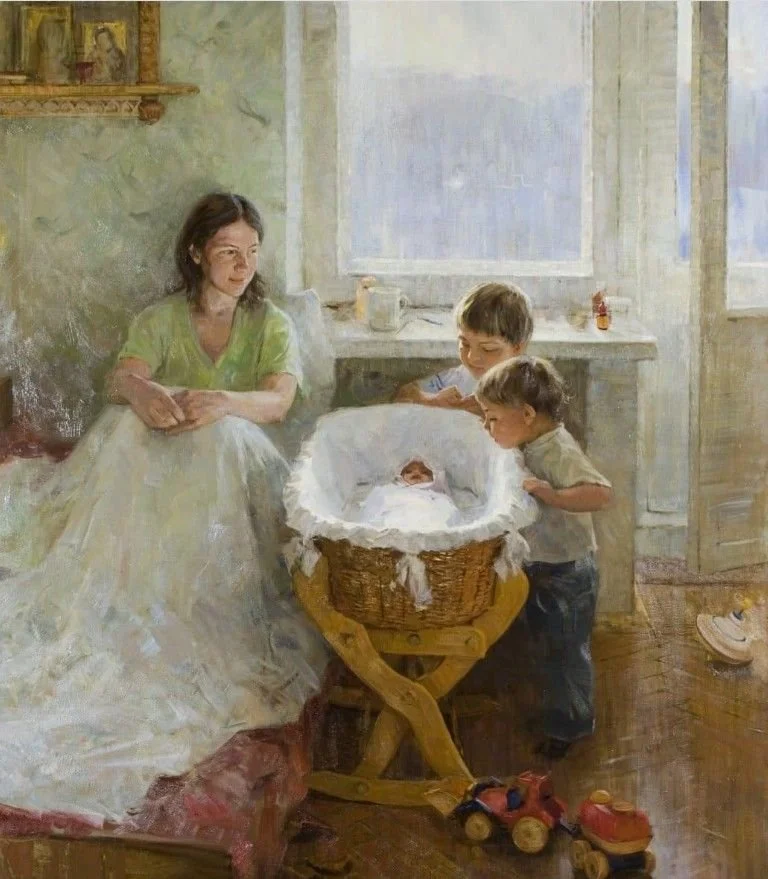 Mom sitting on bed with bassinet beside her with two toddler boys peeking into the bassinet