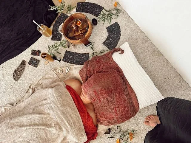 A woman laying down with a wet cloth over her face wrapped in a bunch of fabric