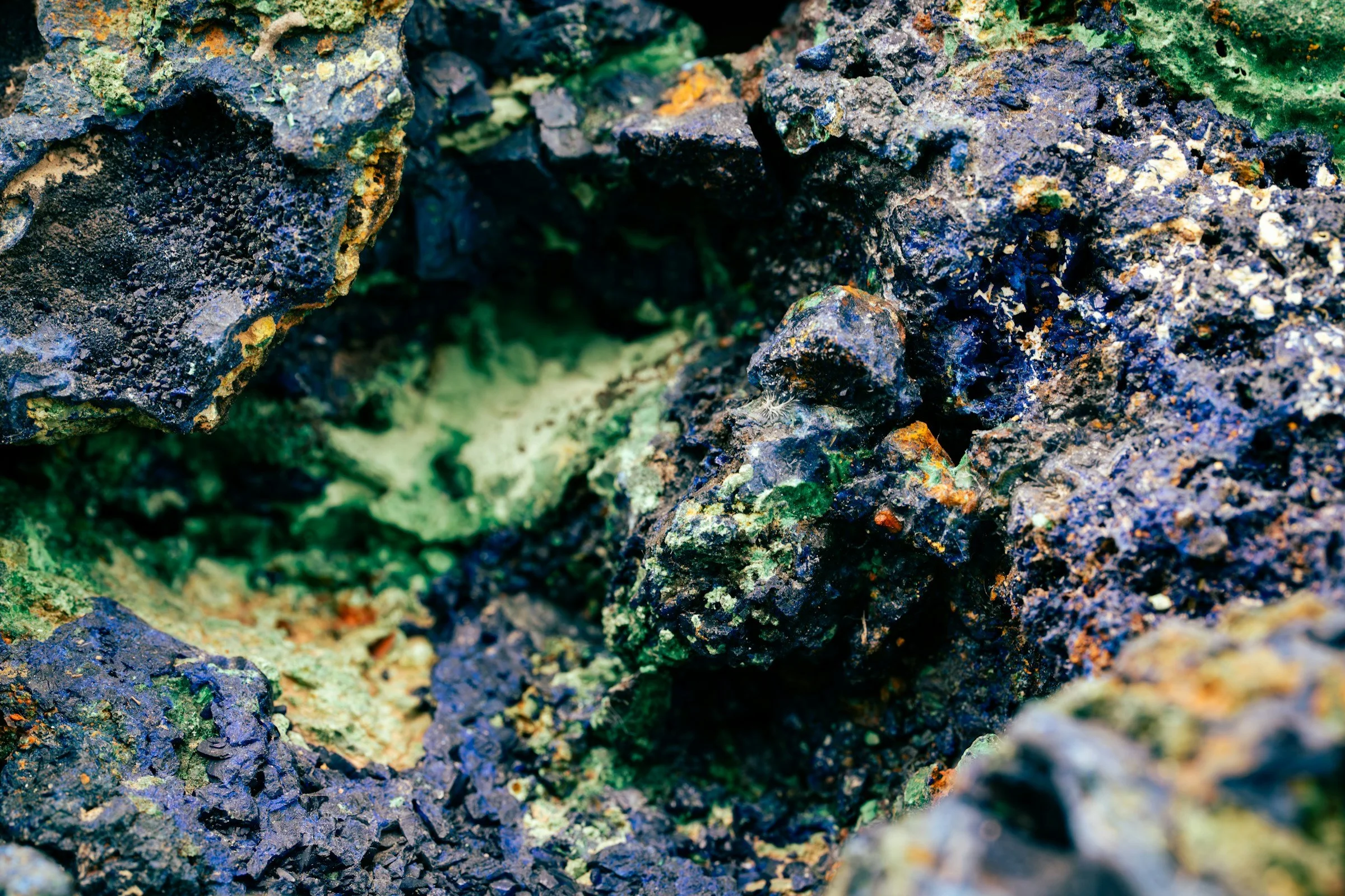 Macro close-up of textured mineral rock in blue, green, and orange.