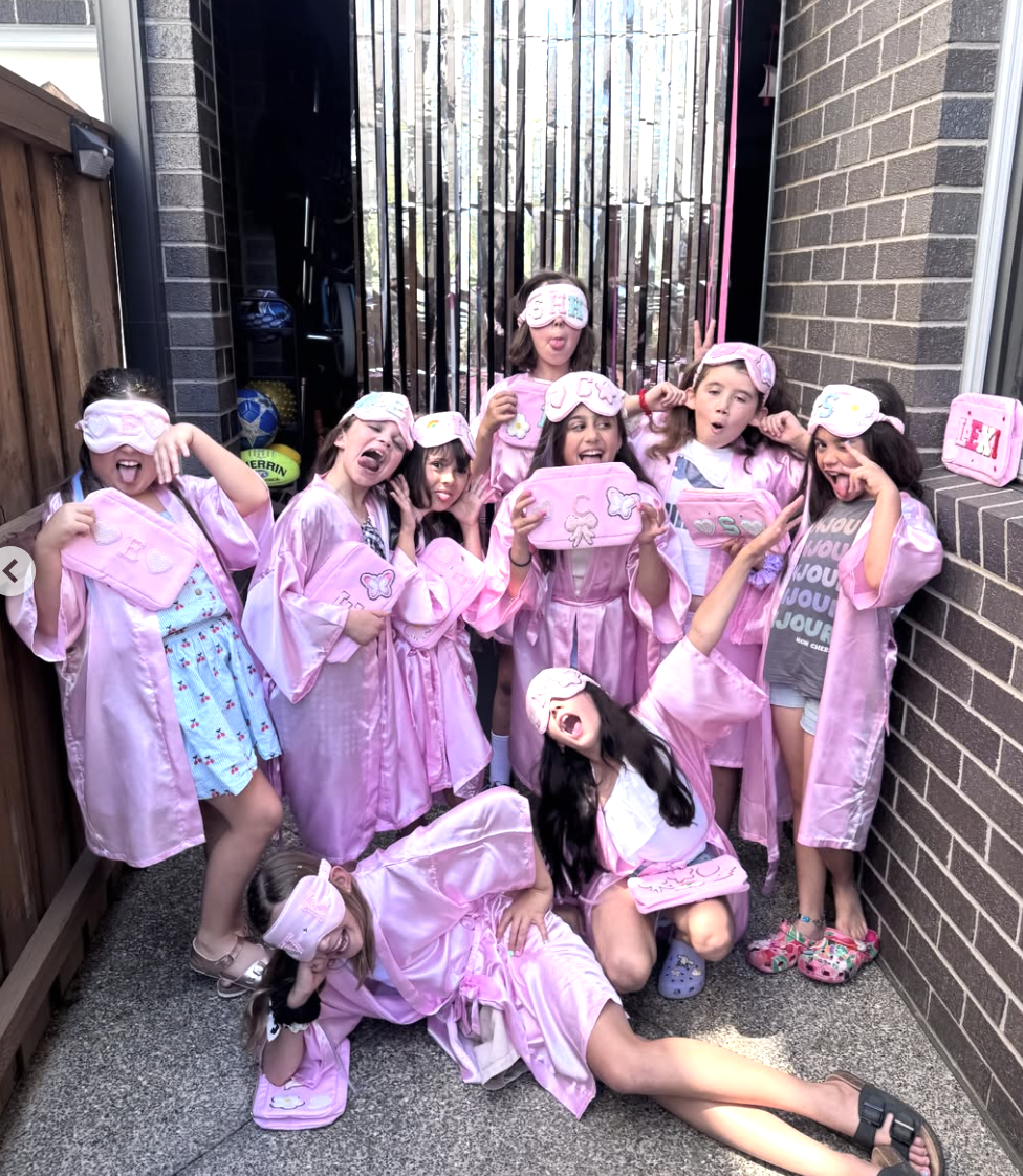 Group of young girls in pink pajamas and sleep masks posing playfully outdoors. Kids Soiree pamper party