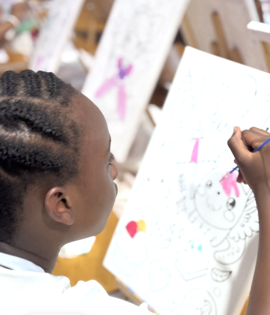 Child with braided hair coloring on an art canvas at an art studio. canvas painting kids soiree
