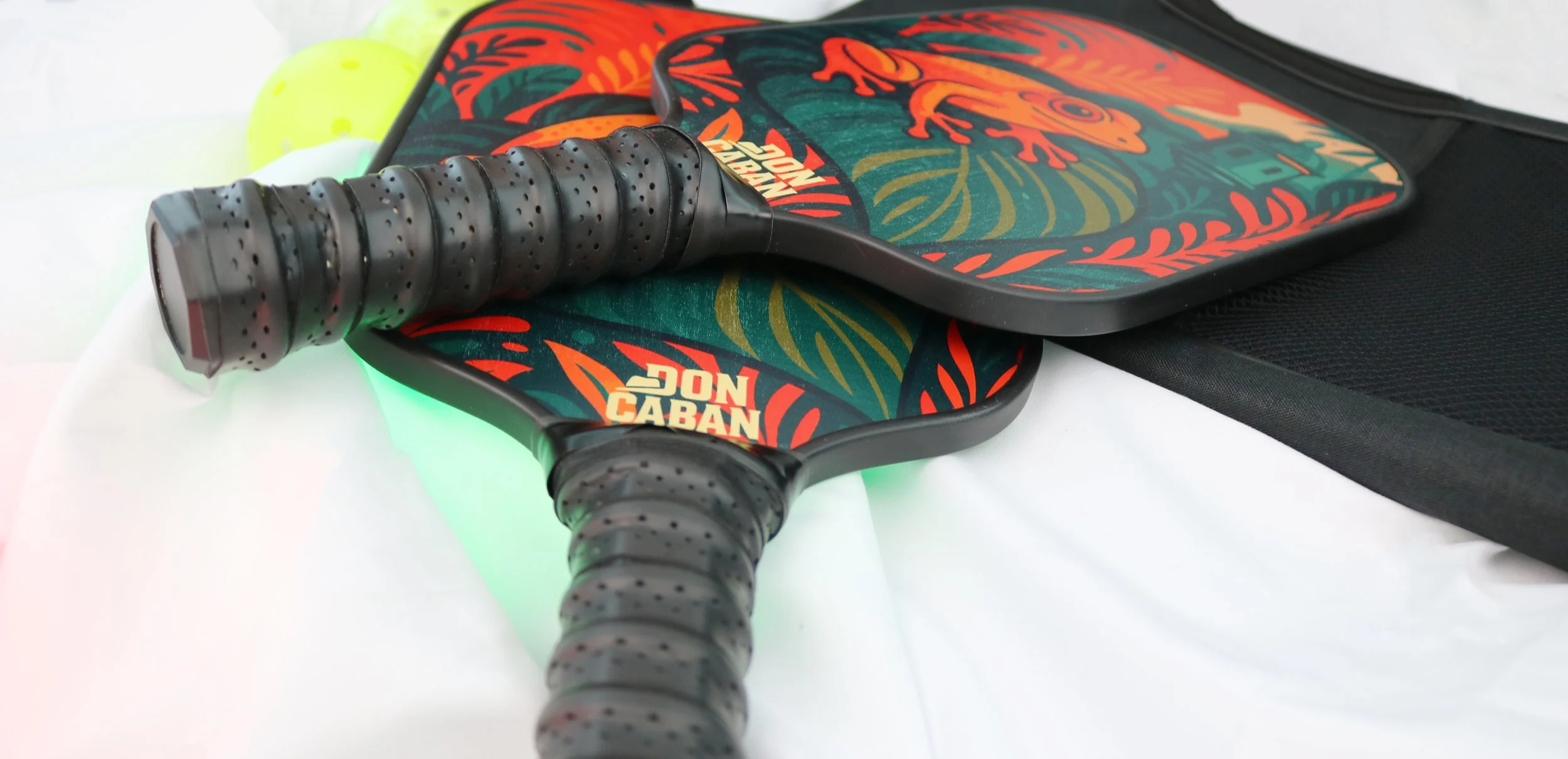 A pickleball paddle set with the FAUNA Coquí design, along with pickleball balls and a black carry bag.