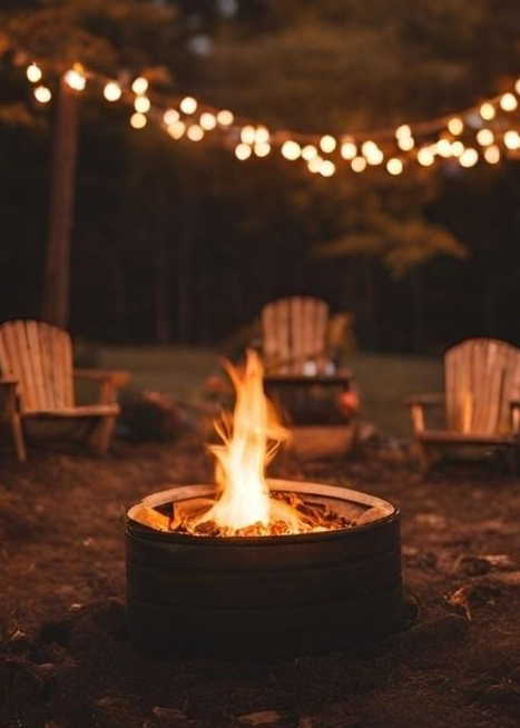a campfire in the forest surrounded by chairs