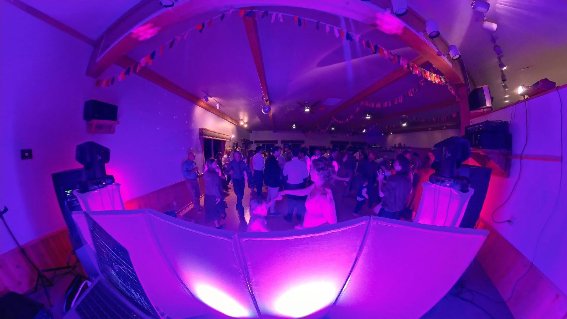 People dancing at a party under purple lighting with disco balls and decorations.