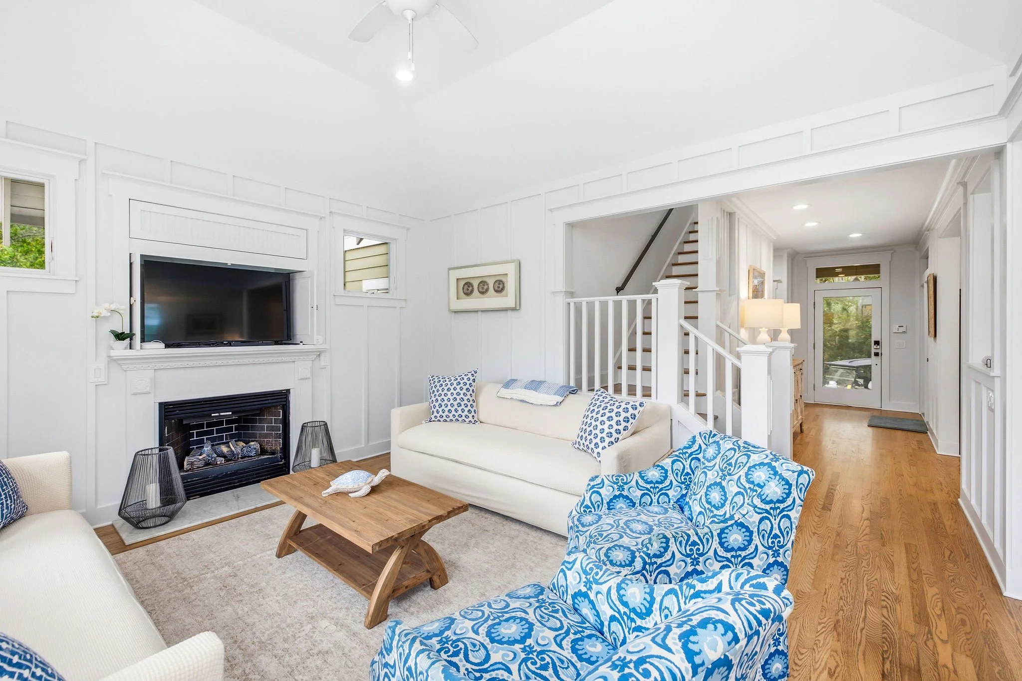 Living room at Sand Dollar Dreamin, a Bald Head Island vacation rental, with fireplace, ceiling fan, two white sofas and blue coastal decor