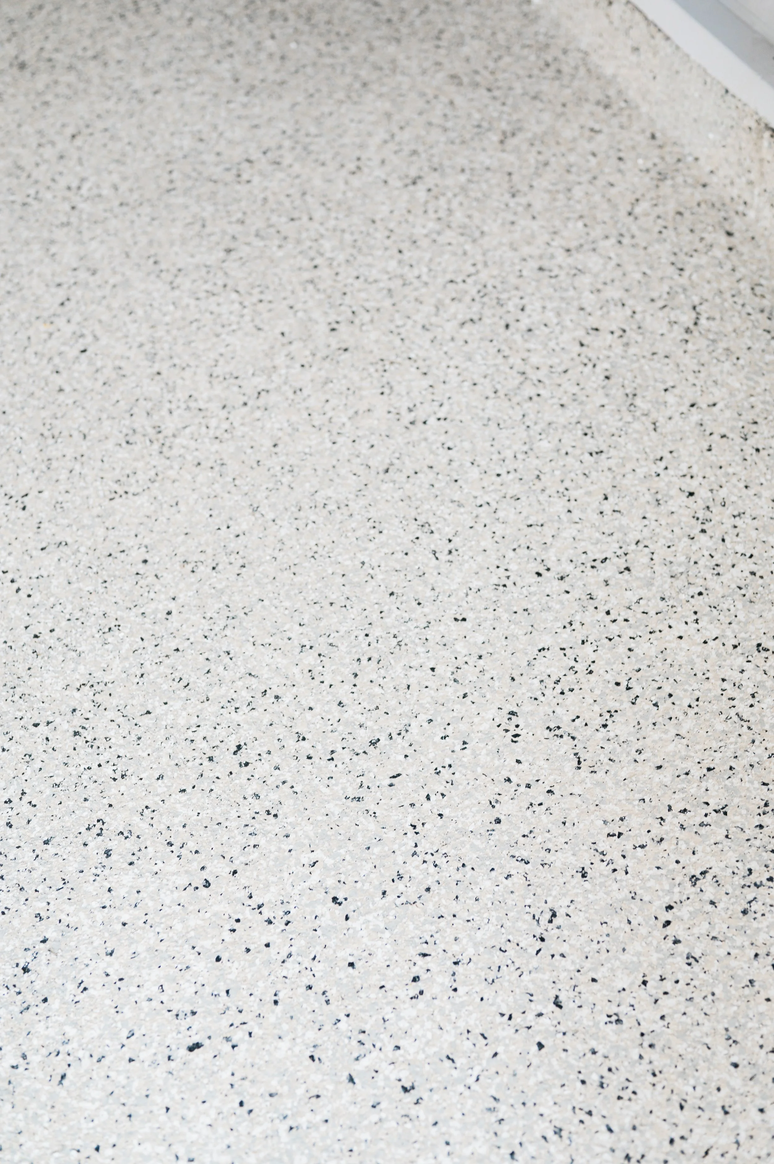 Close-up of beige speckled countertop or flooring surface with small black and white specks.