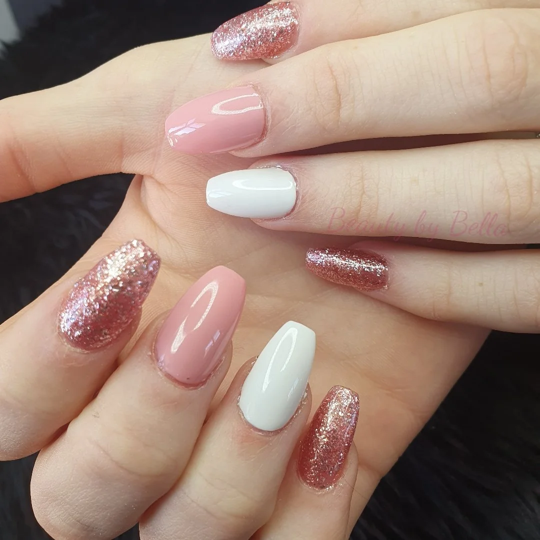 Close-up of hands with manicured nails featuring pink, white, and rose gold glitter polish.