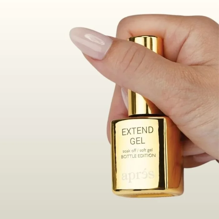 Hand holding a small gold bottle of Aprés Extend Gel, a soak-off soft gel product.