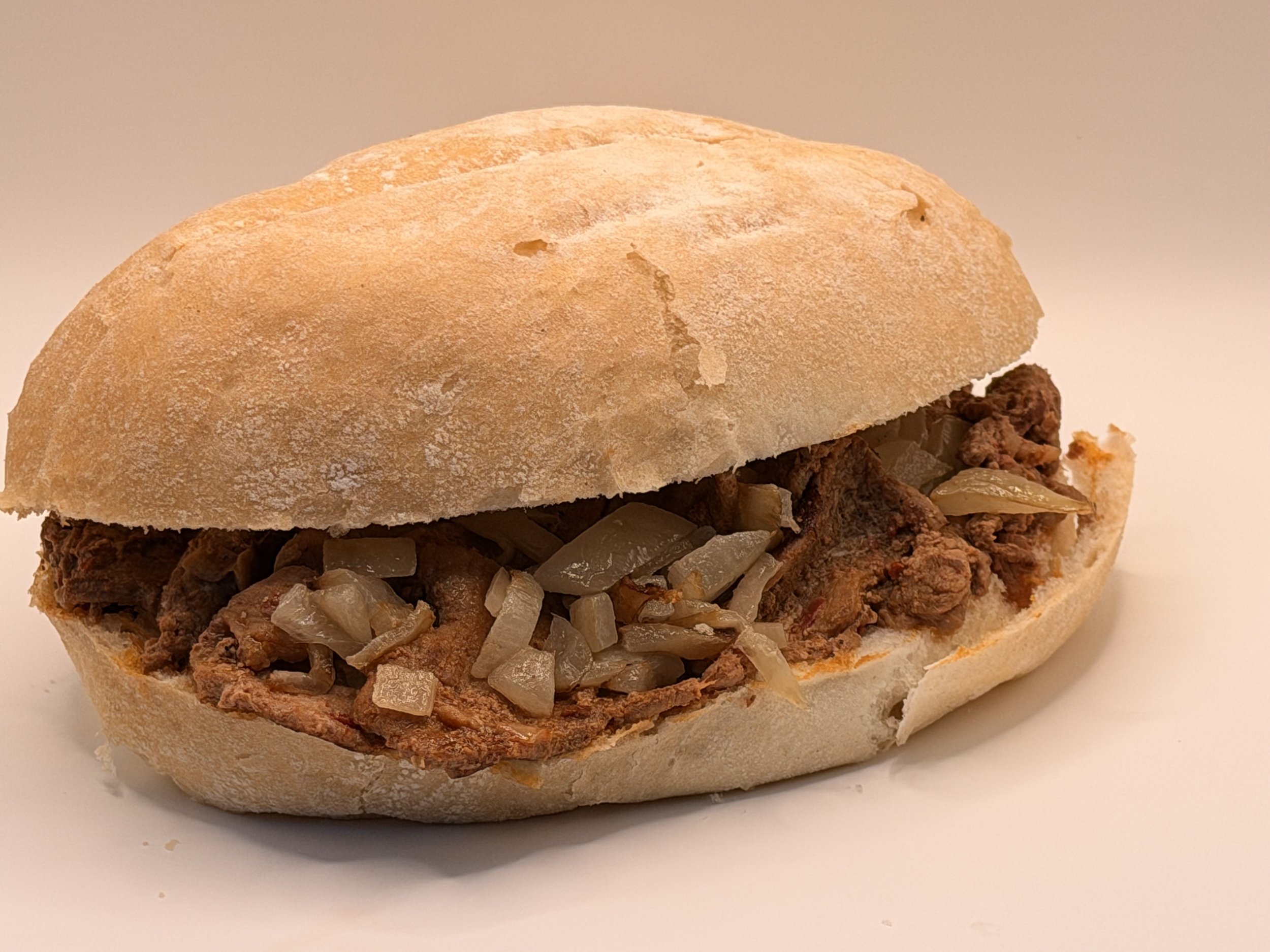 Close-up of a beef sandwich with chopped onions in a sandwich bun