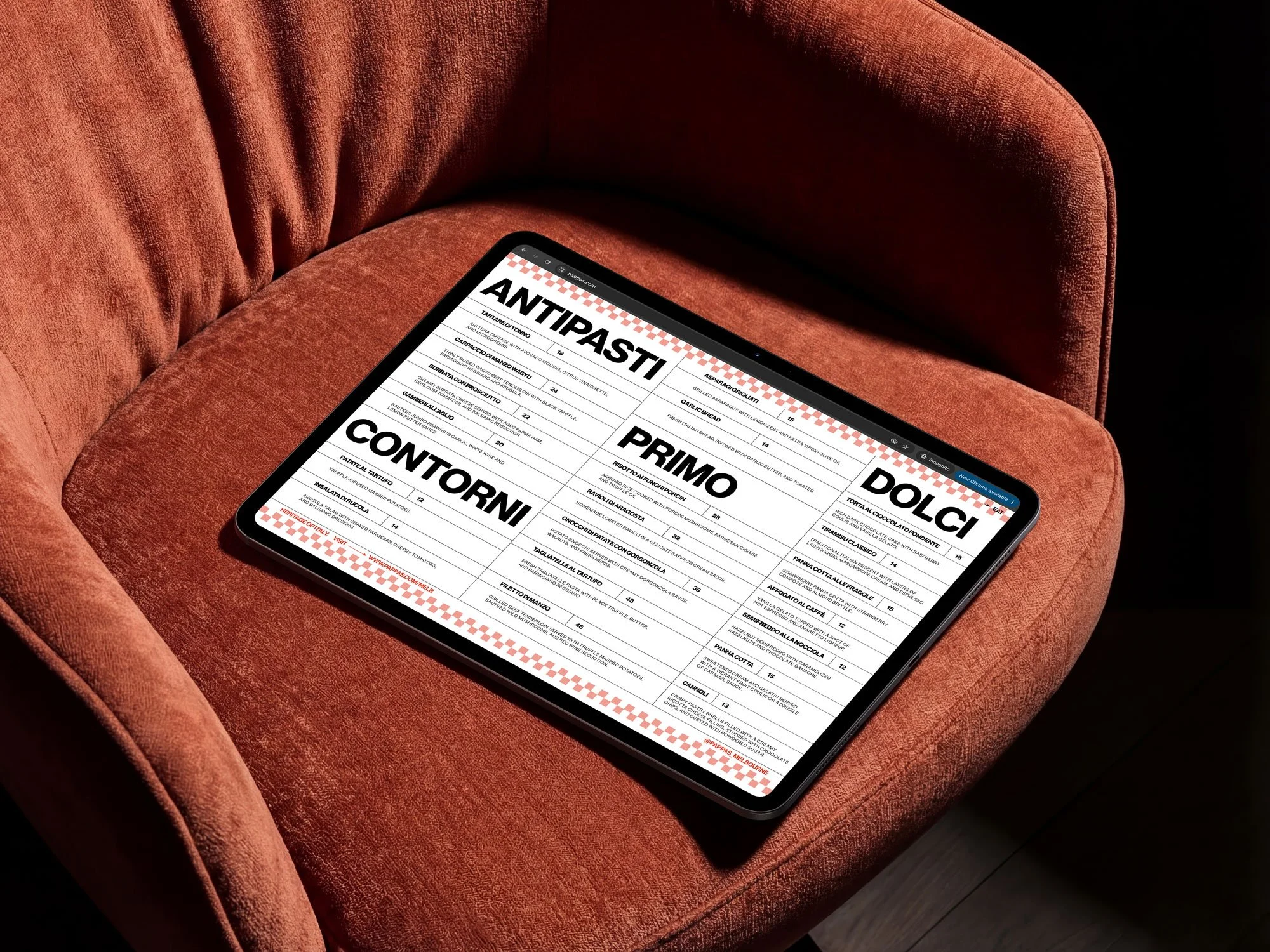 Tablet displaying an Italian restaurant menu resting on a red velvet armchair.