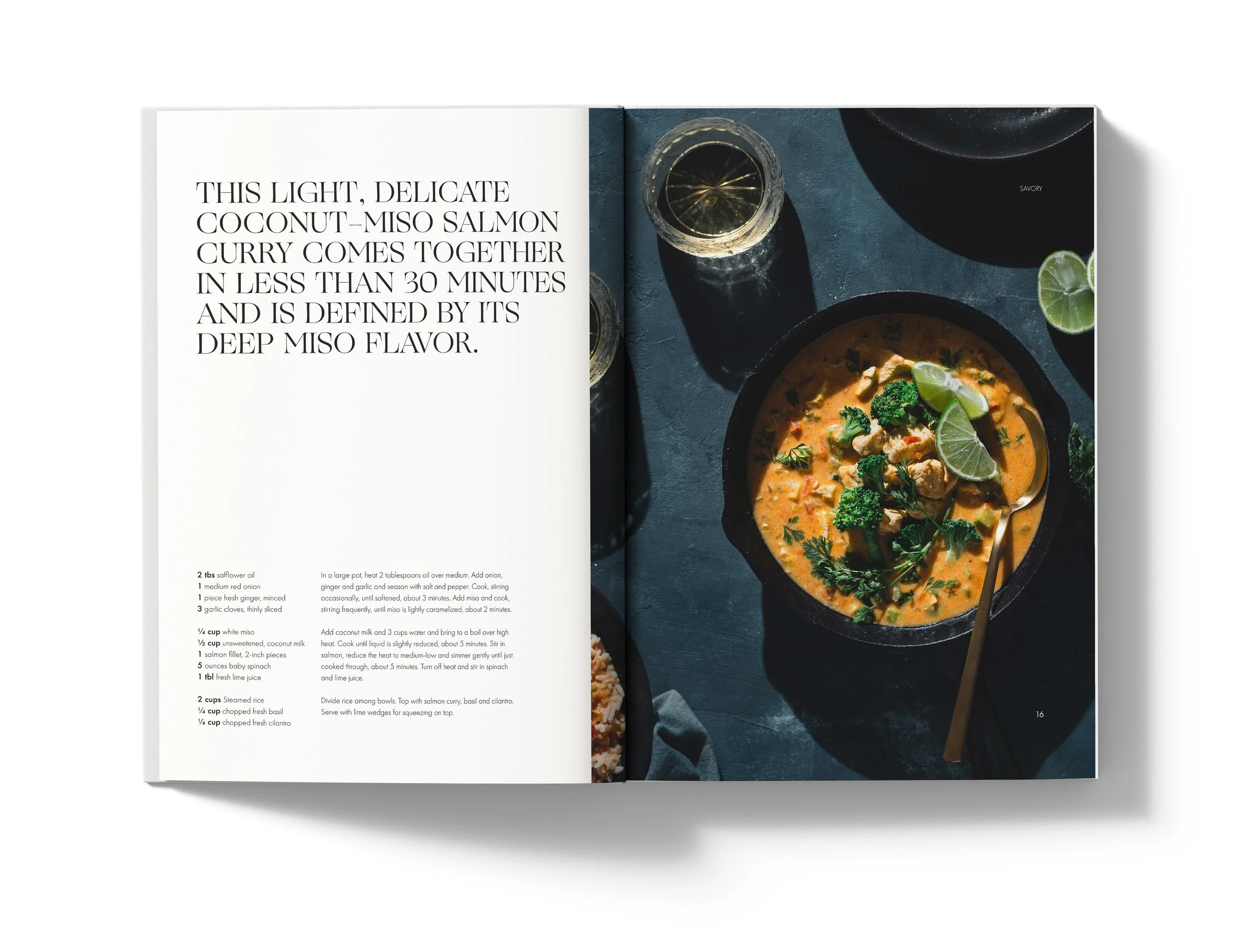 Open cookbook showing a recipe page with text and a photograph of Vietnamese fish curry with lime wedges in a black bowl, garnished with herbs, on a dark surface.